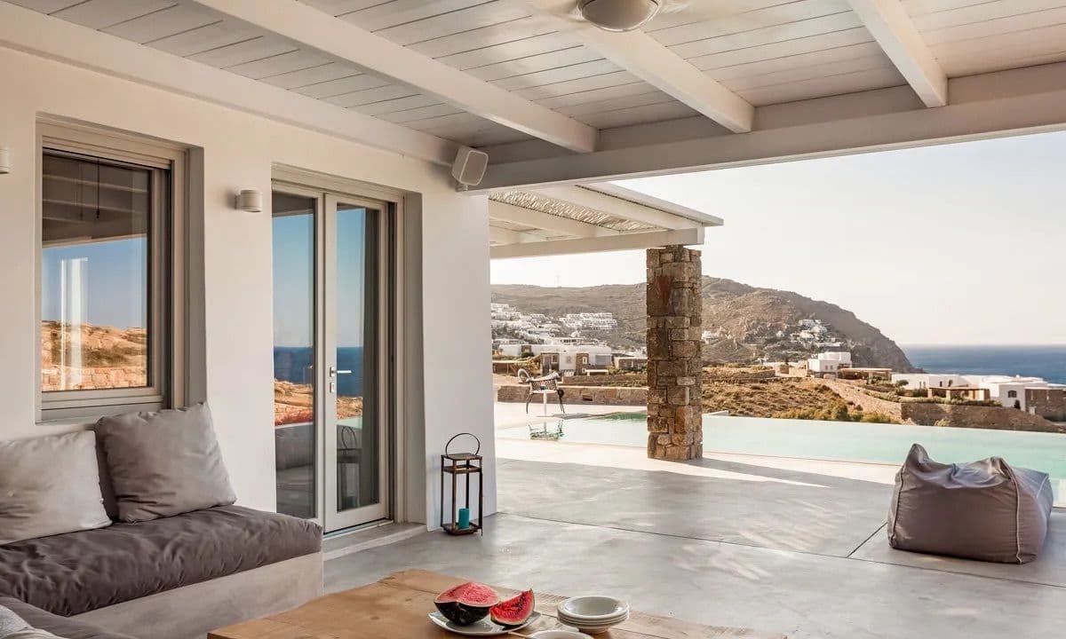 Covered terrace with sofas looking over the pool to the coast at Ancient Azure Vistas, Mykonos