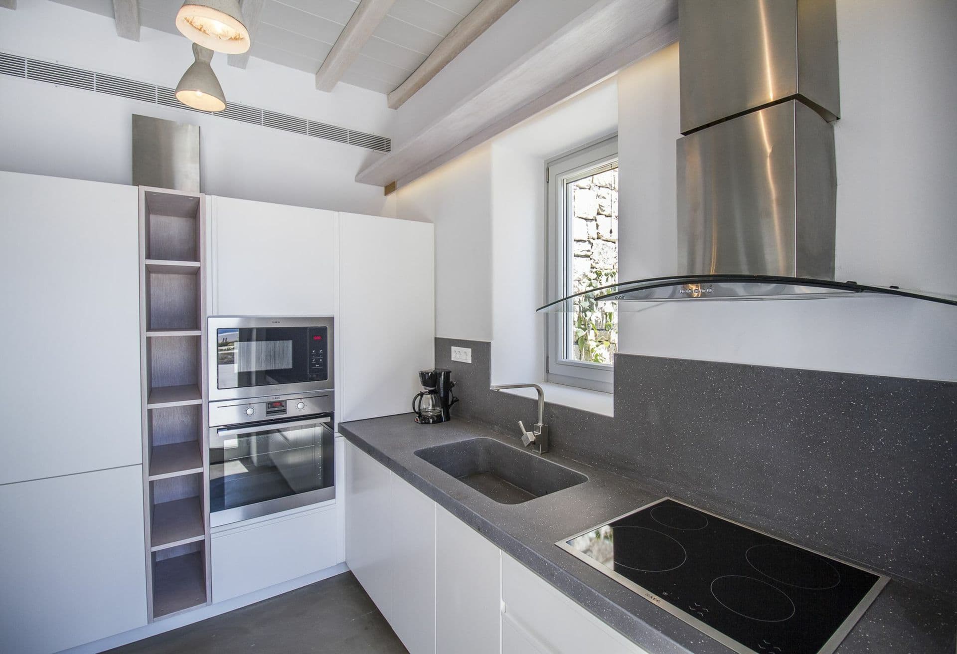 White kitchen with stone worktops and a stainless extractor at Ancient Azure Vistas, Mykonos