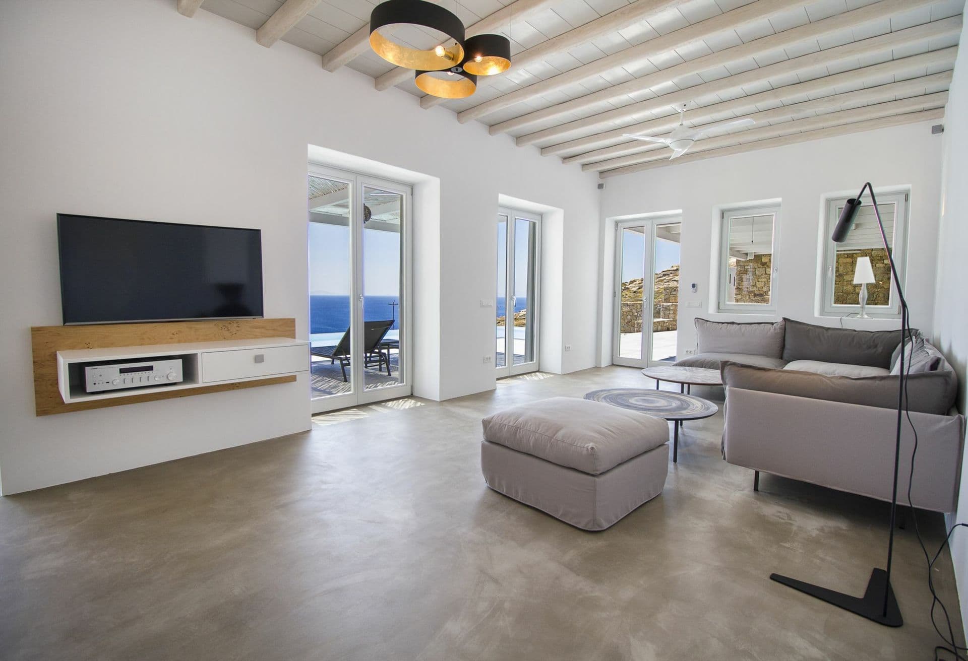 Media lounge with a television and sea views under a beamed white ceiling at Ancient Azure Vistas, Mykonos