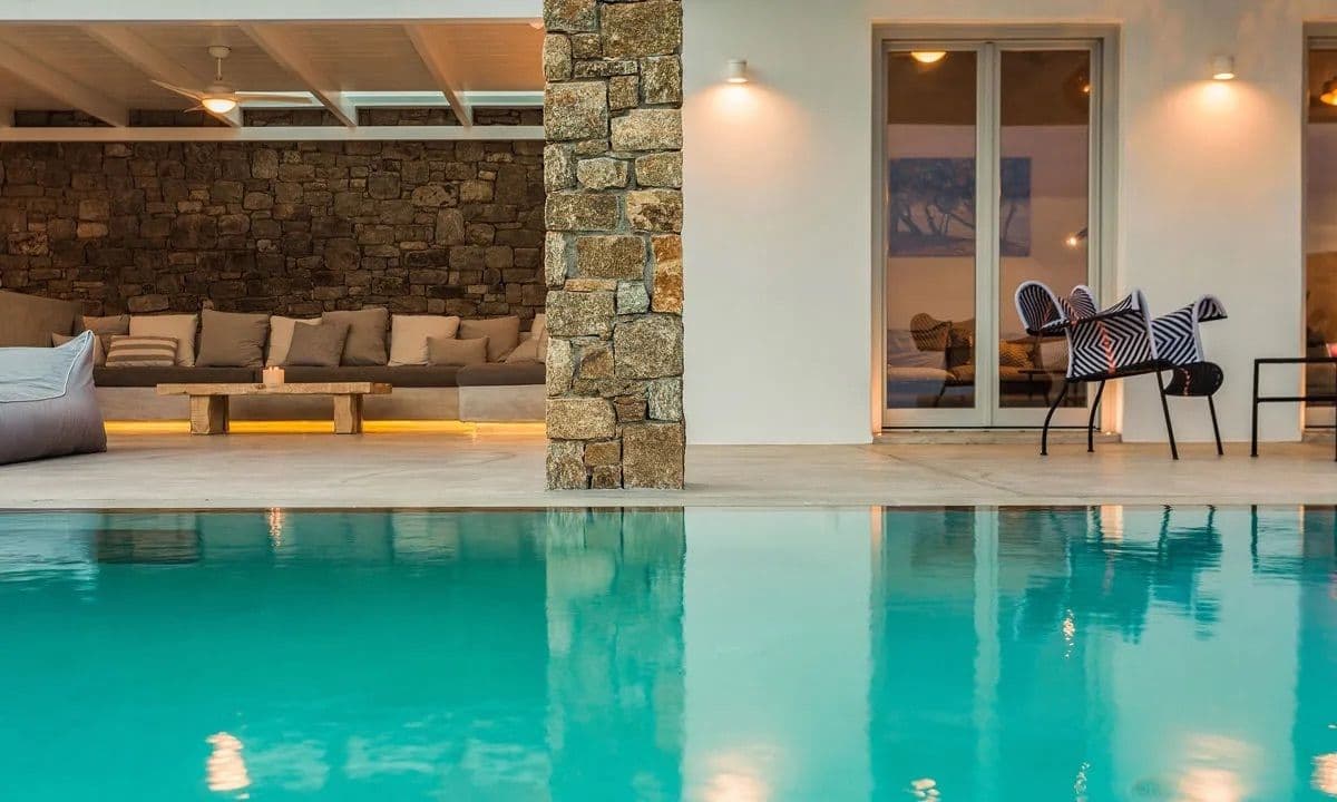 Covered poolside lounge with day beds against a stone wall at Ancient Azure Vistas, Mykonos