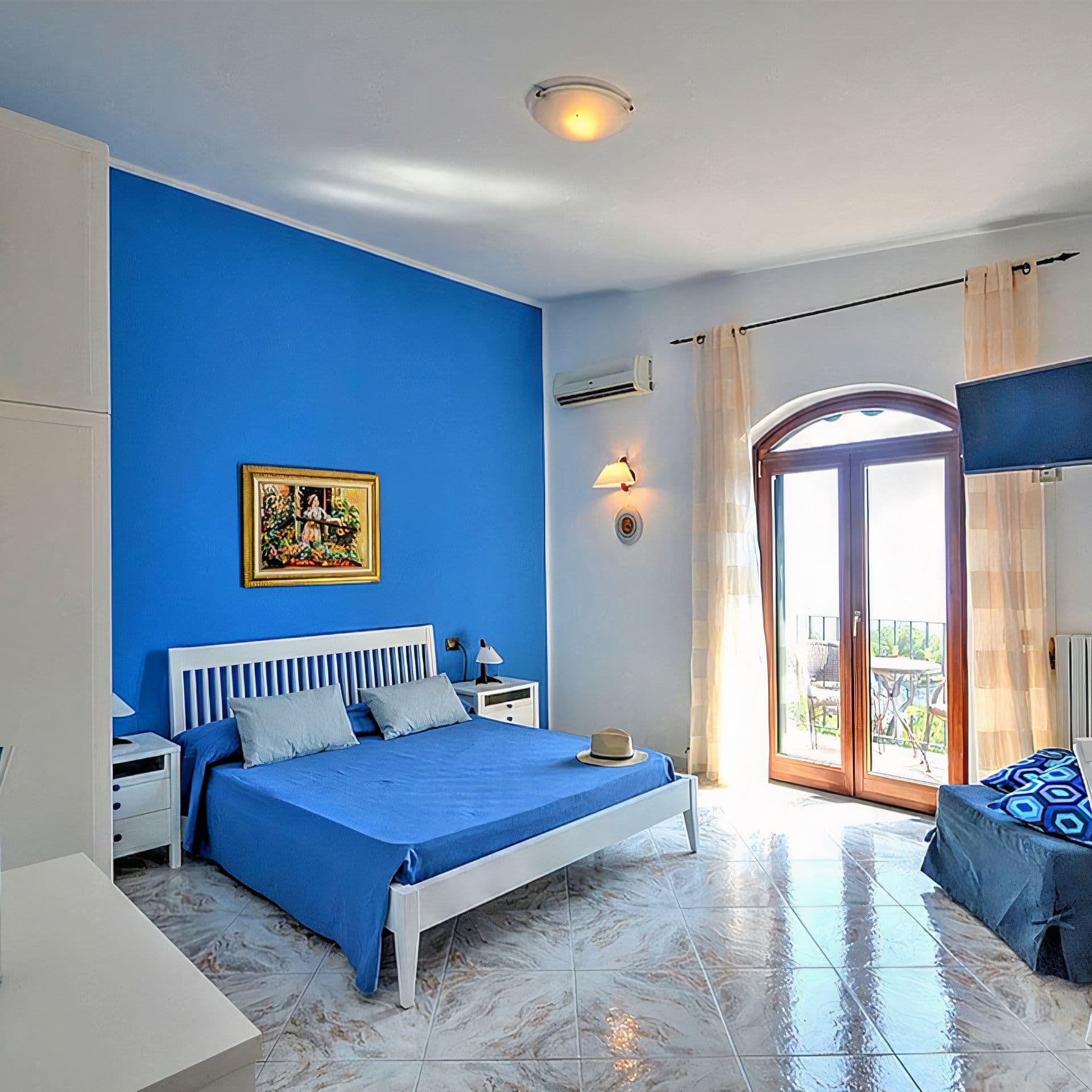 A bedroom with a wrought iron bed and blue accent wall beside a garden window
