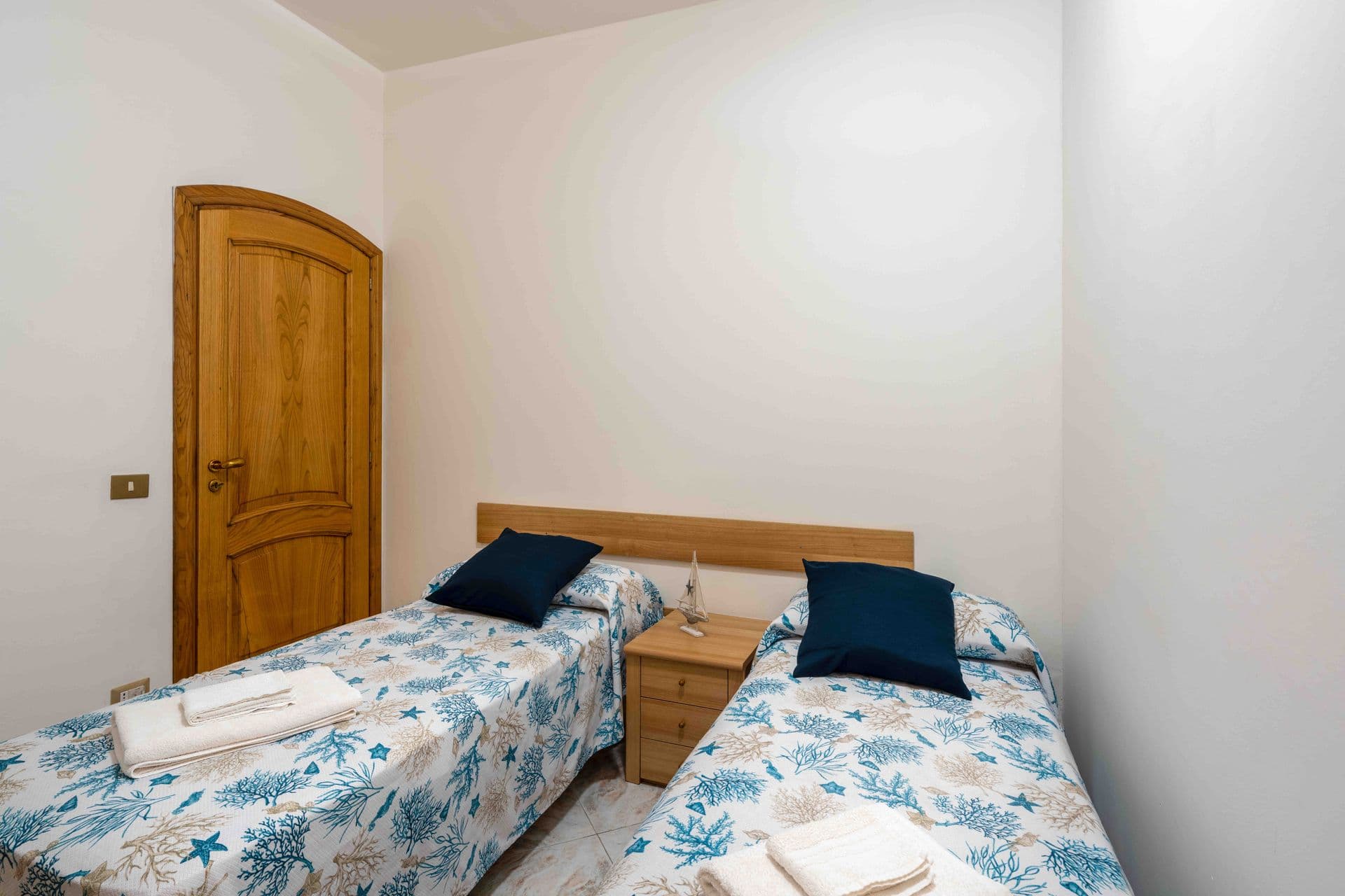 A twin bedroom with coastal print bedspreads and matching bedside tables