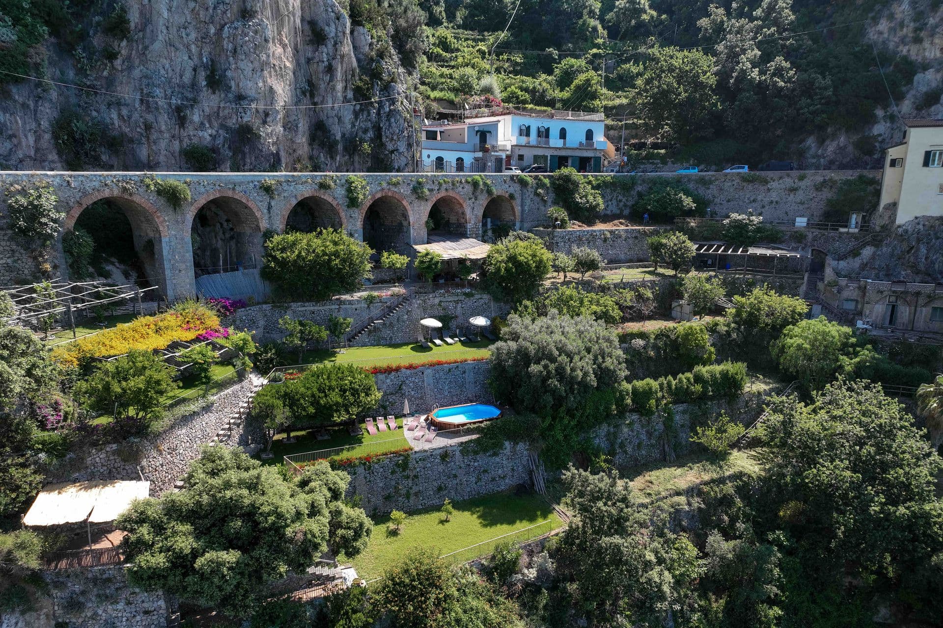 Aerial view of The Magic of Amalfi, a terraced cliffside villa with pool and archways above the Amalfi coast