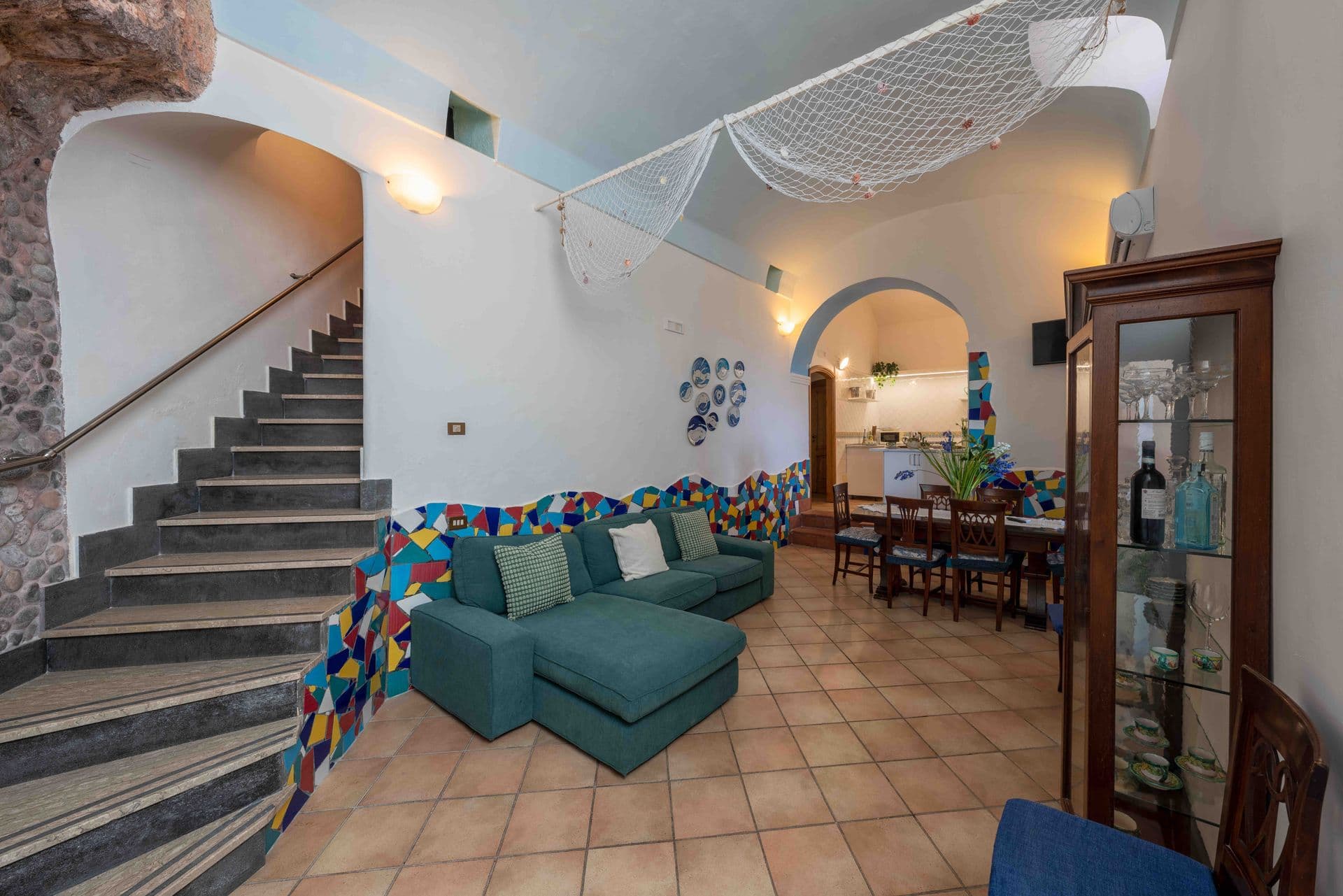 A colourful mosaic staircase feature beside a teal sofa and dining table