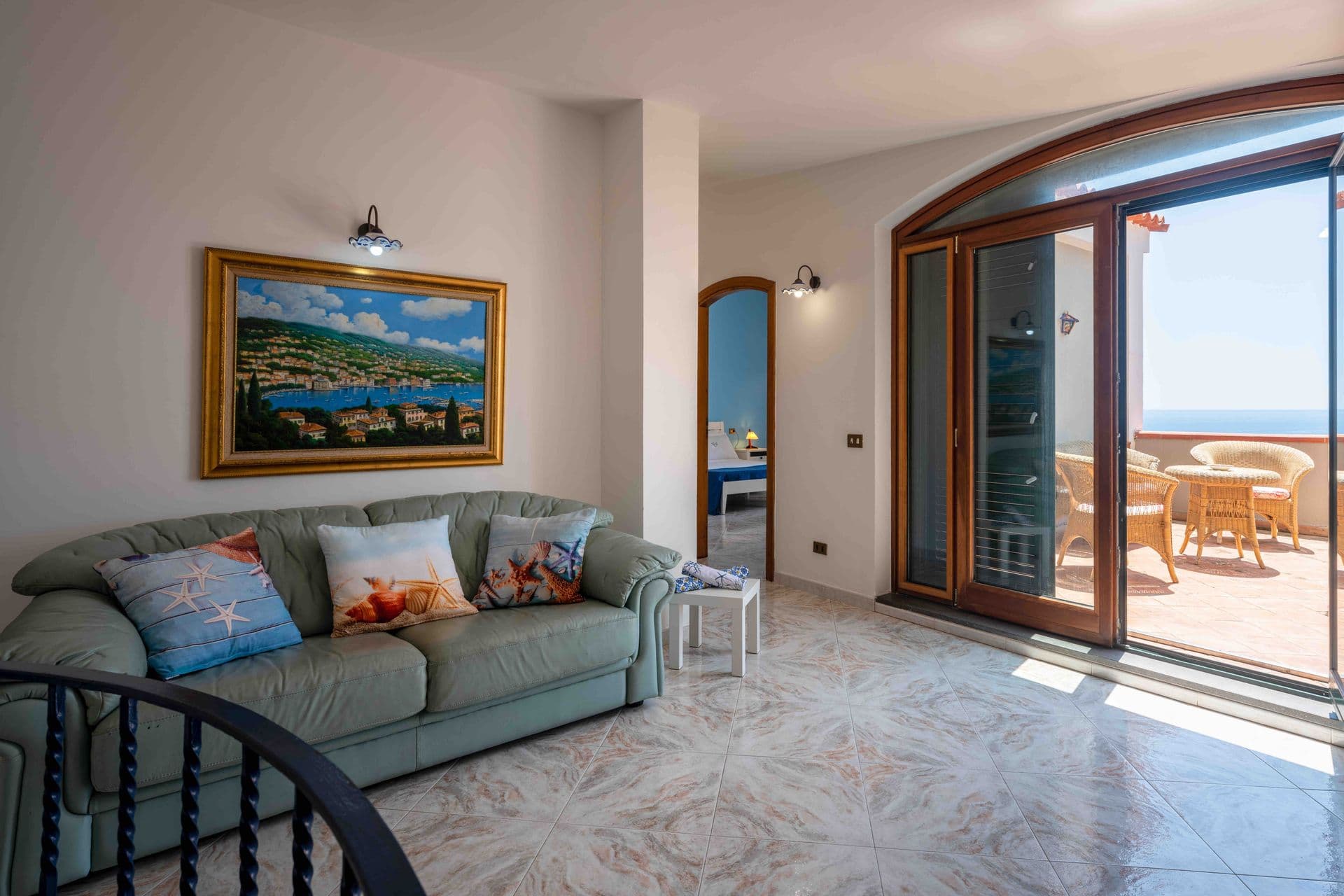A living room sofa facing glazed doors that open onto the sea view terrace