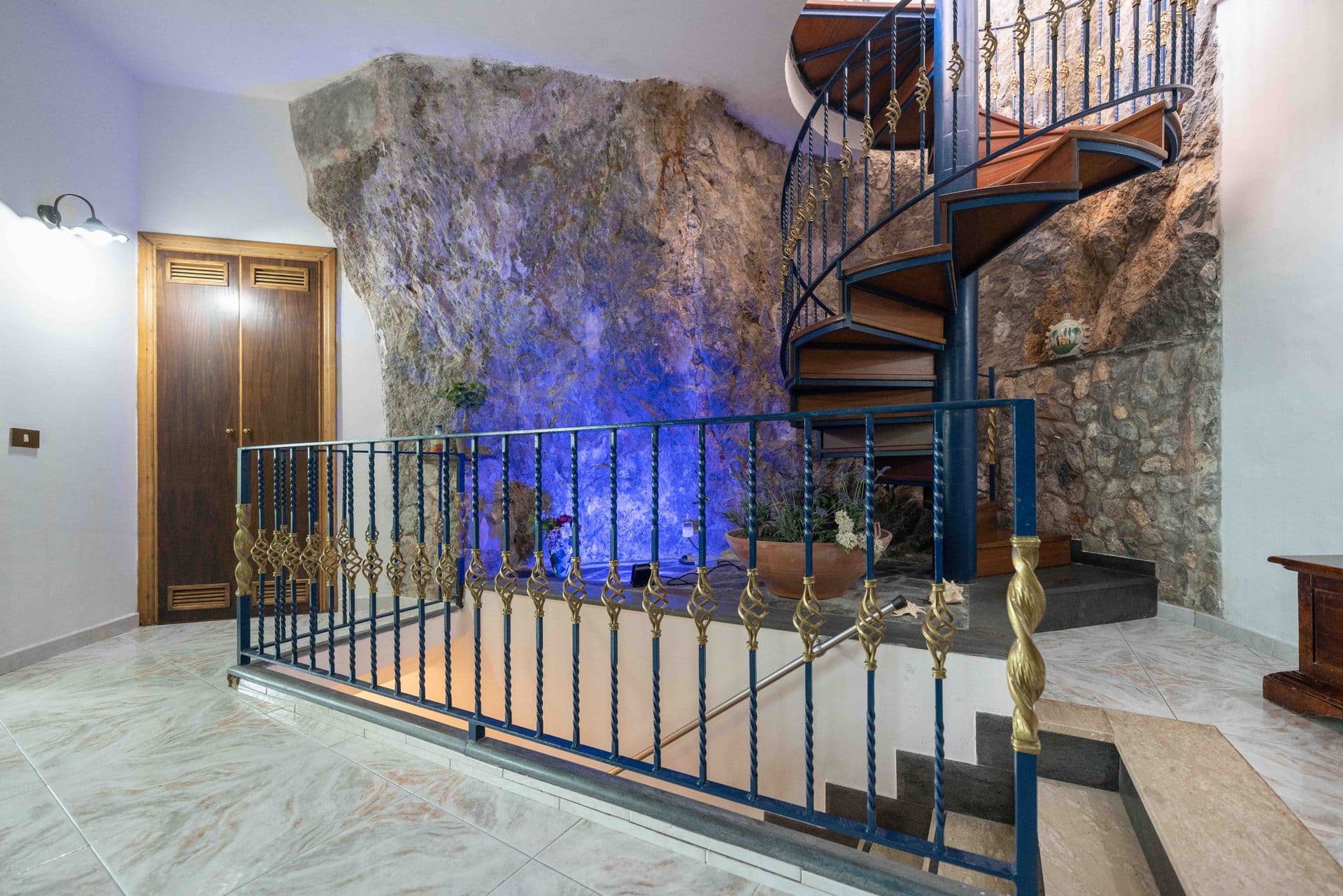 A wrought iron spiral staircase set against a natural rock wall feature