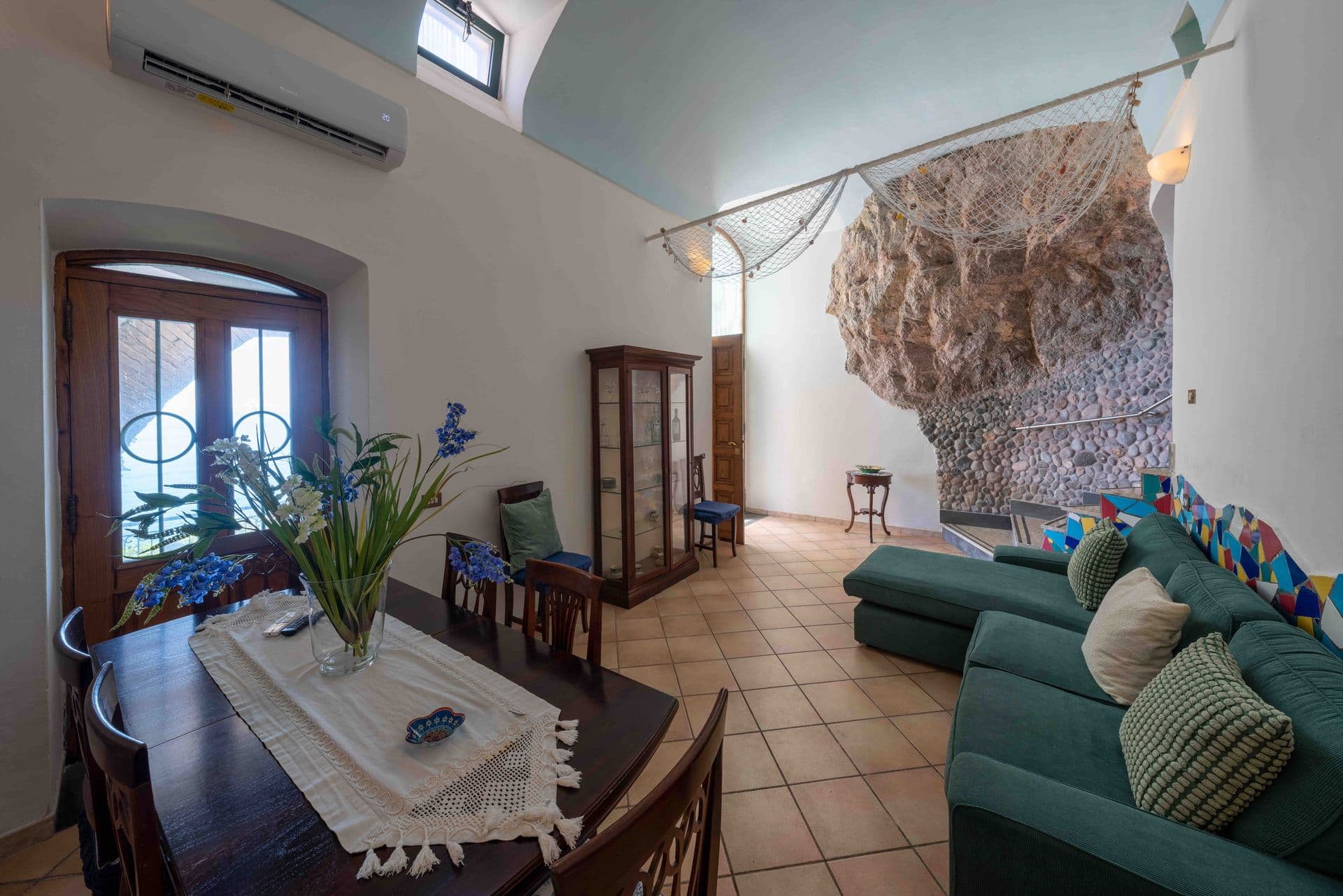 A high ceilinged living room with a natural stone archway and sea view balcony