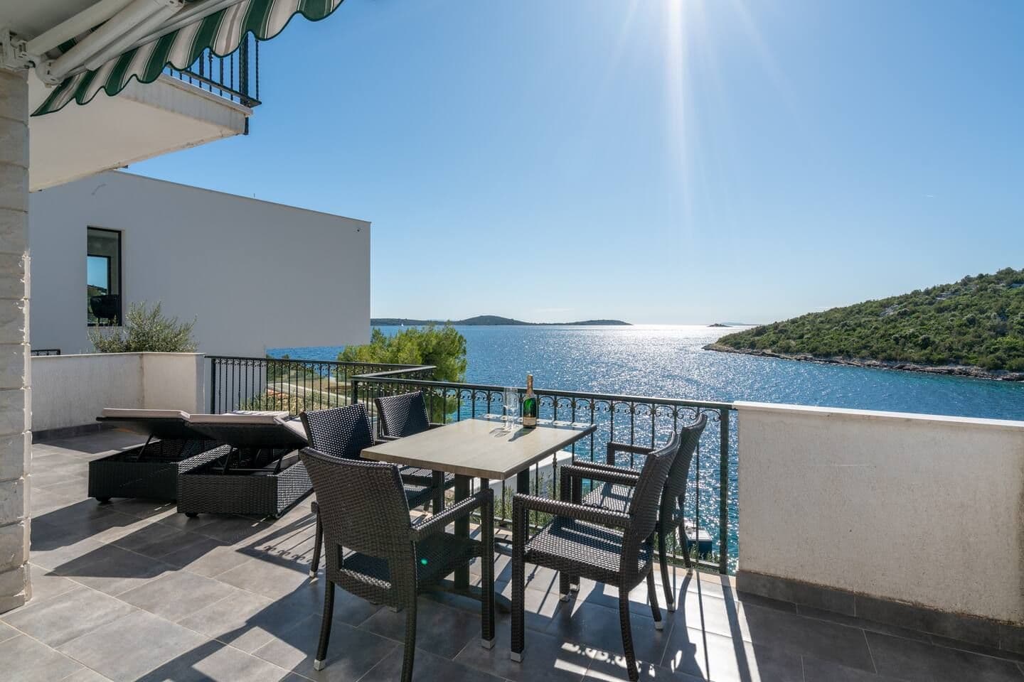 Covered terrace with a stone barbecue and a long bench table at Blue All Around, Marina, Croatia