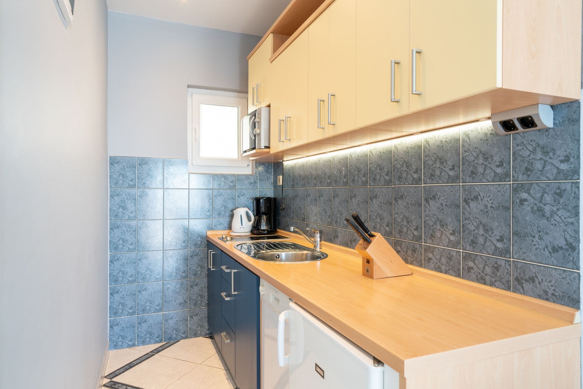 Compact kitchenette in teal and white with a dining table at Blue All Around, Marina, Croatia