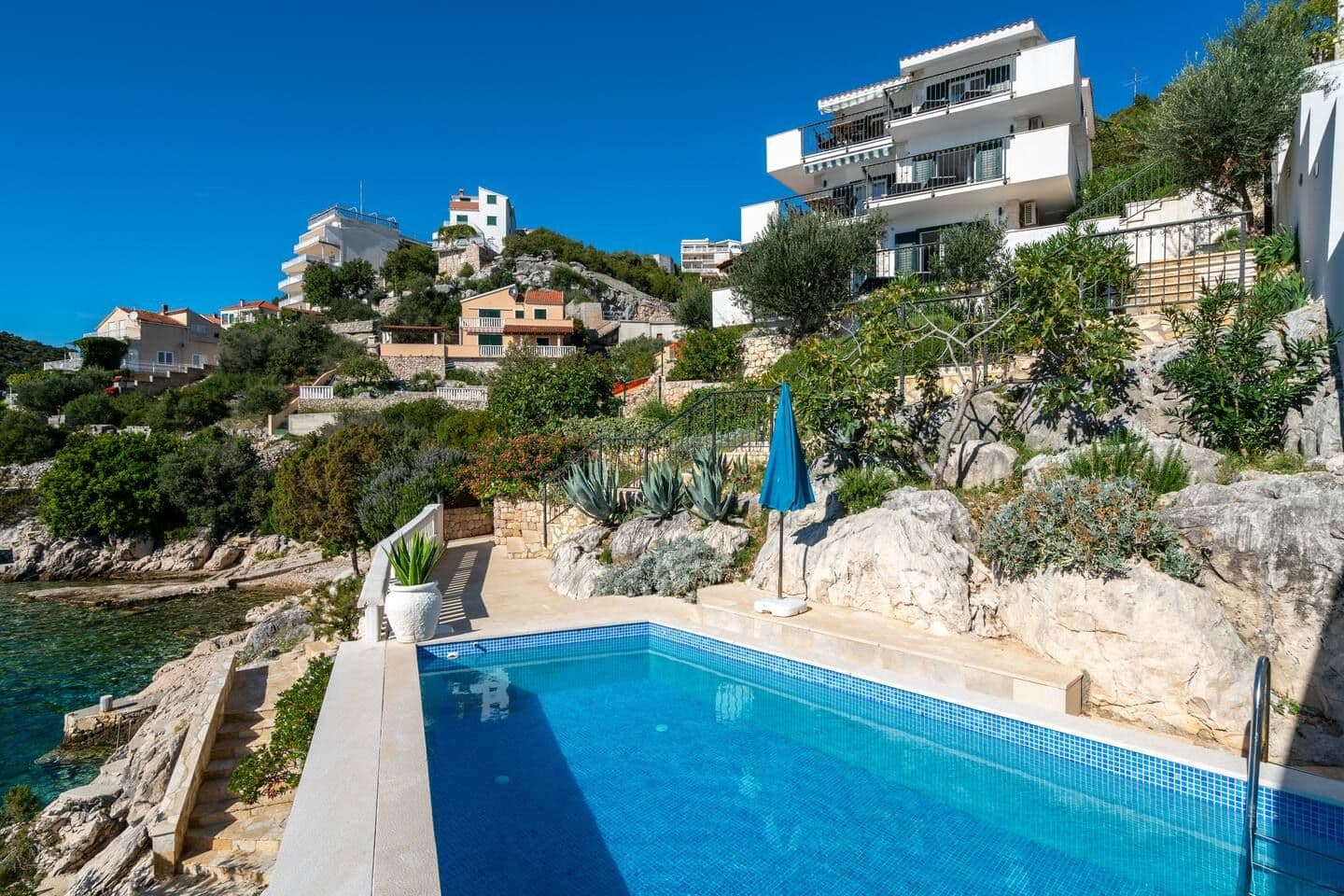 White waterfront villa with terraced gardens above a cove at Blue All Around, Marina, Croatia