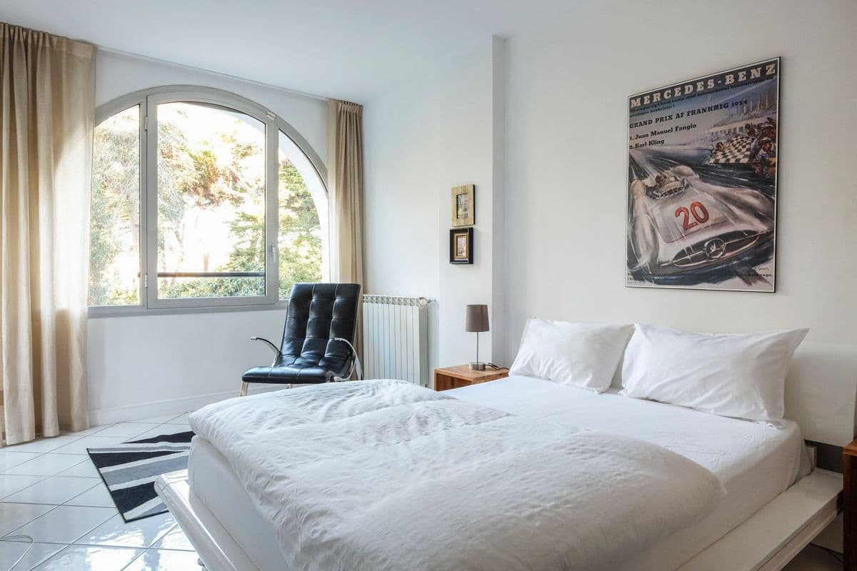 Bedroom with an arched window and framed vintage racing poster