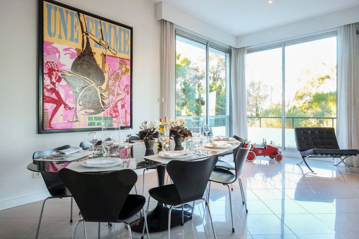 Dining room with glass walls, colourful artwork and a table set for a meal