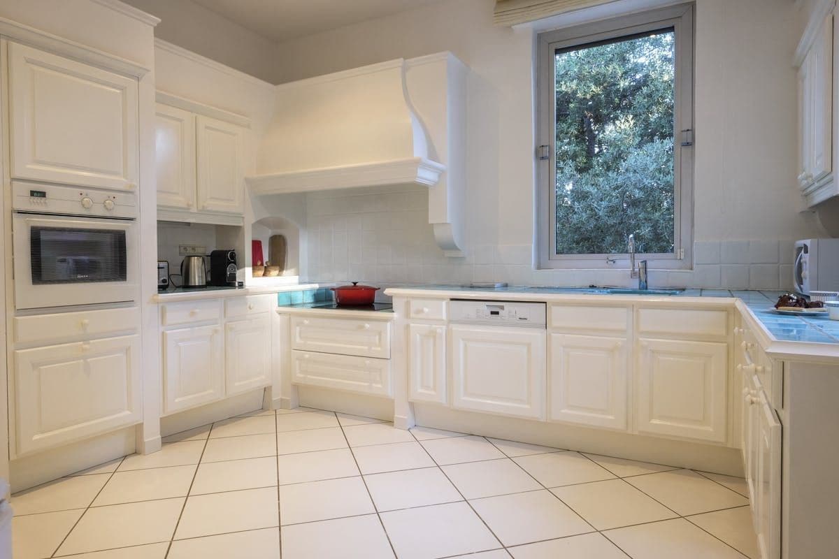 Kitchen with cream cabinetry, tiled floor and garden-facing window