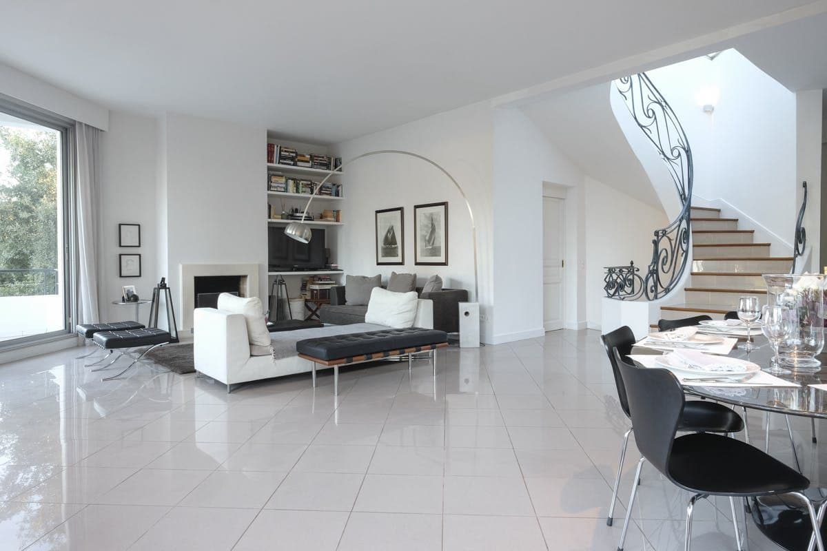 Living room with white sofa, fireplace and spiral staircase behind