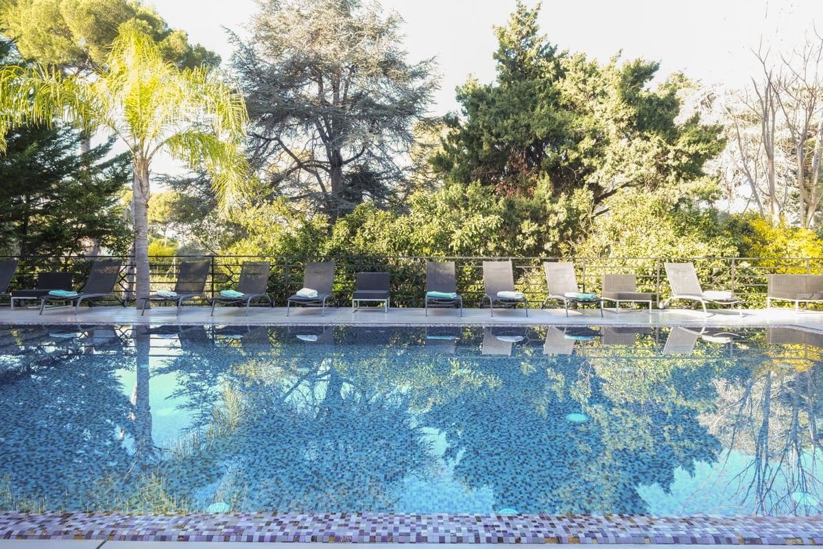 Long dark pool bordered by loungers and mature pine trees