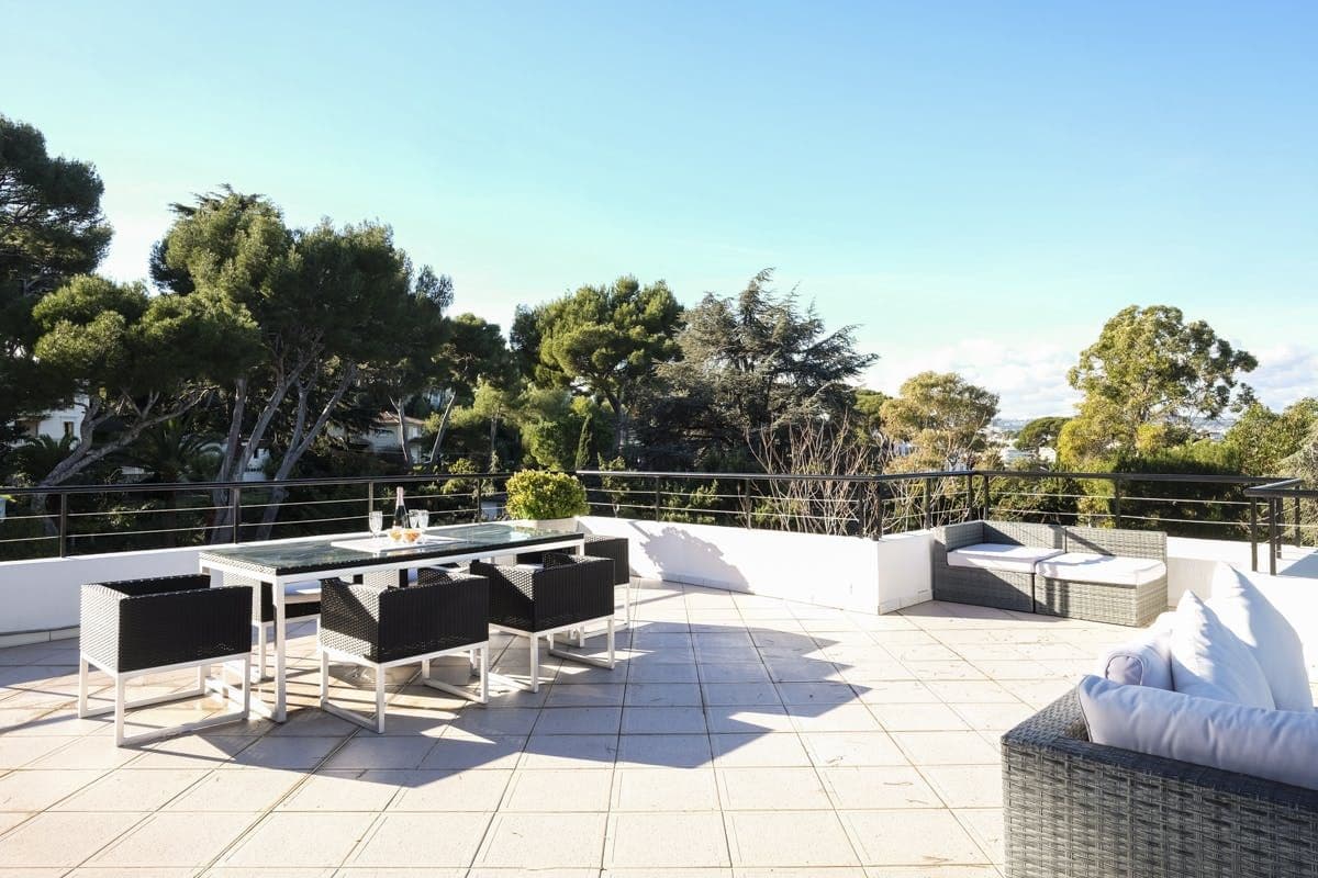 Rooftop terrace with rattan dining set and sofa under a clear sky