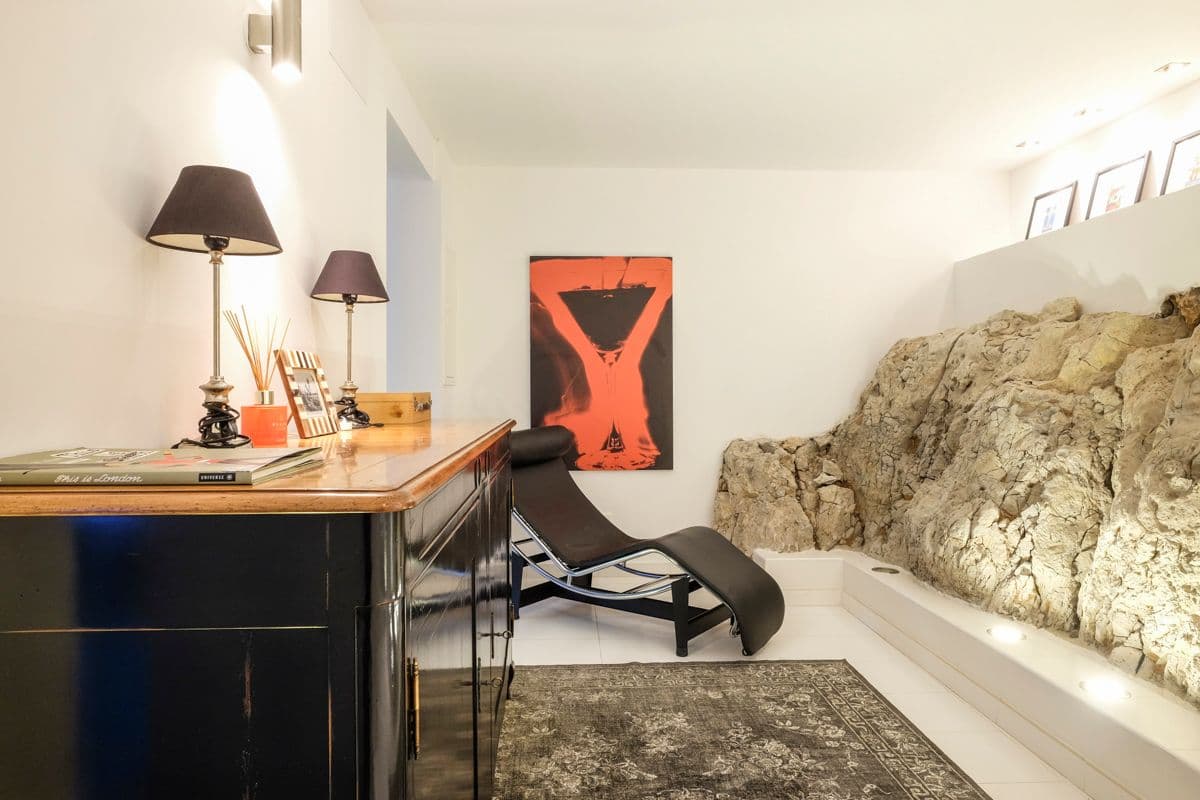 Study with black desk, designer chair and exposed natural rock wall