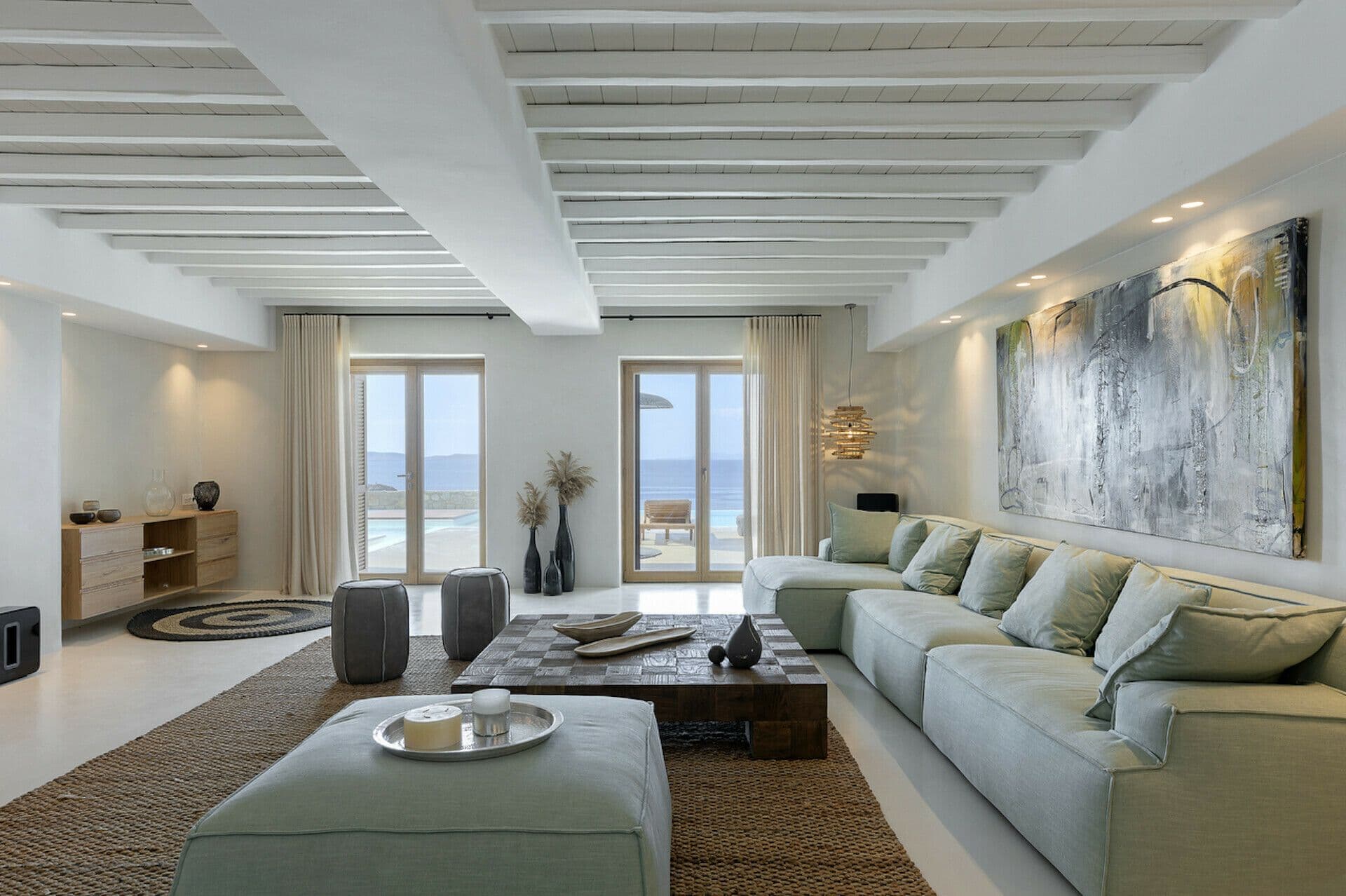 Open-plan lounge with sage-green sofas and abstract artwork at Cycladic Wonder, Mykonos