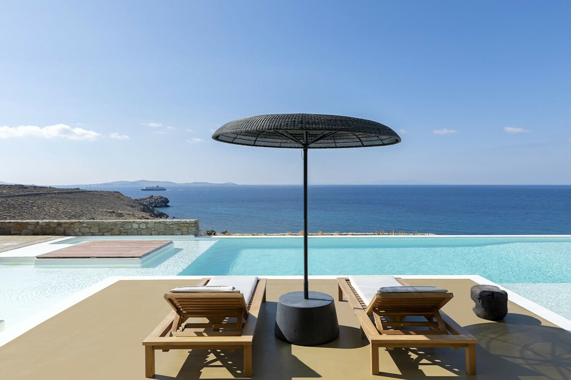 Infinity pool with loungers and a parasol looking out to sea at Cycladic Wonder, Mykonos