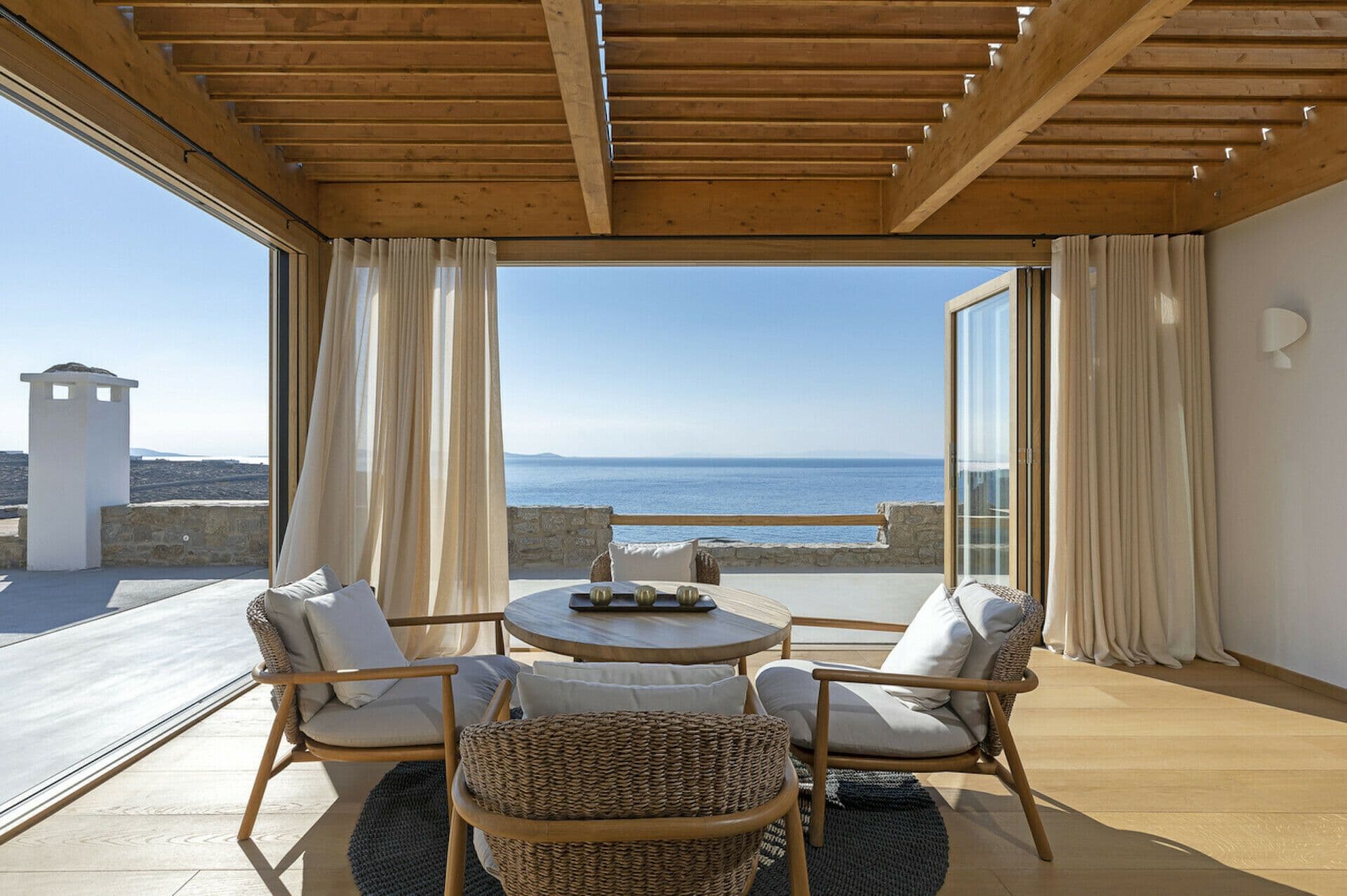 Covered terrace lounge under a timber pergola with sea views at Cycladic Wonder, Mykonos
