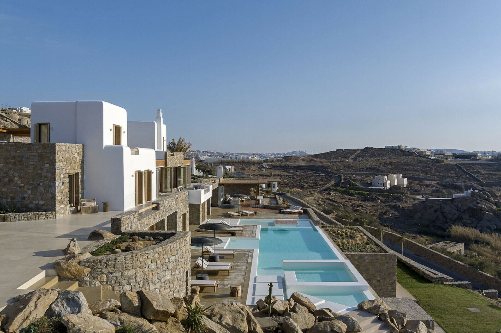 White villa complex with a pool set into the Mykonos hillside above the sea at Cycladic Wonder, Mykonos