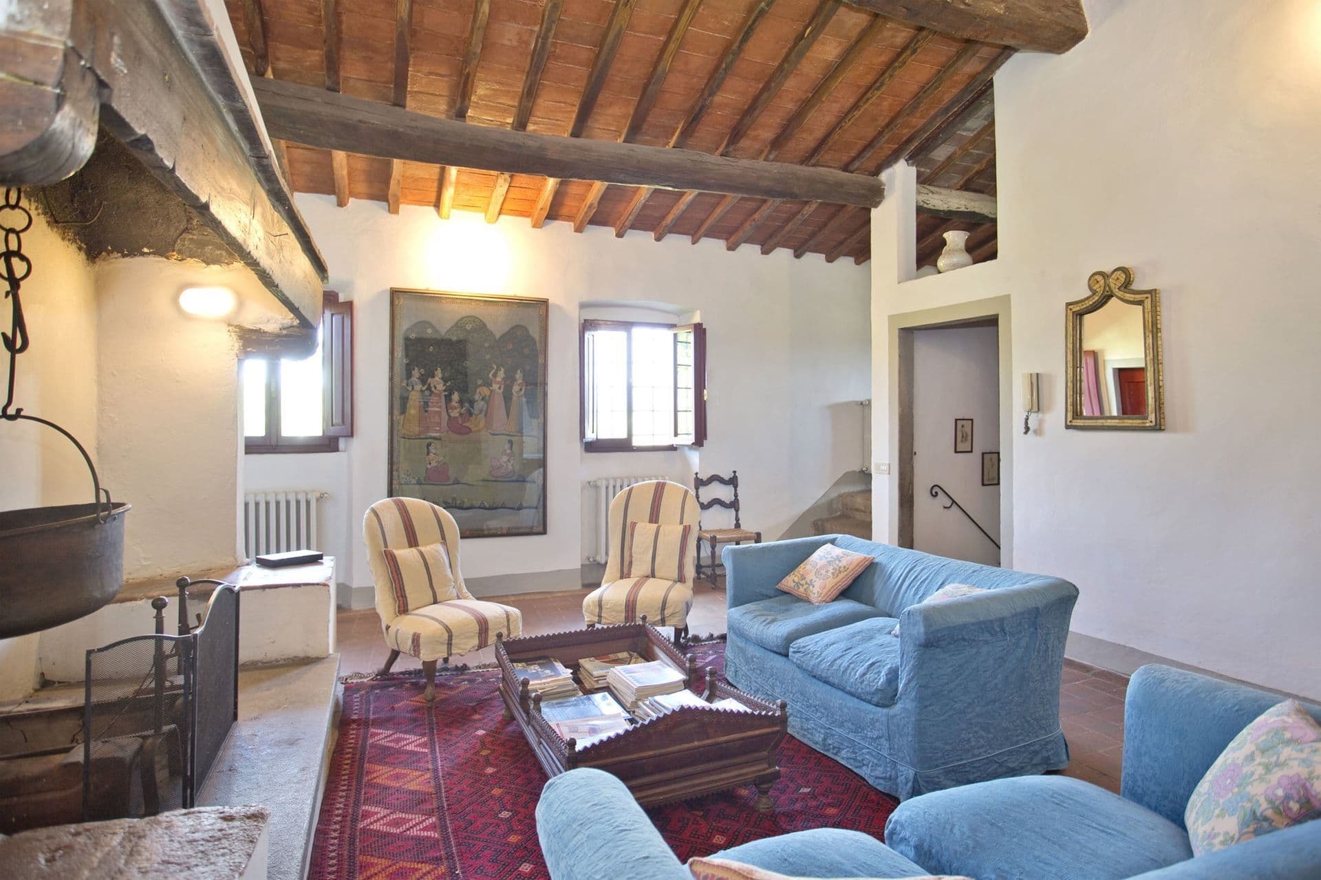 Beamed living room with open fireplace and blue armchairs at Picturesque Hideaway