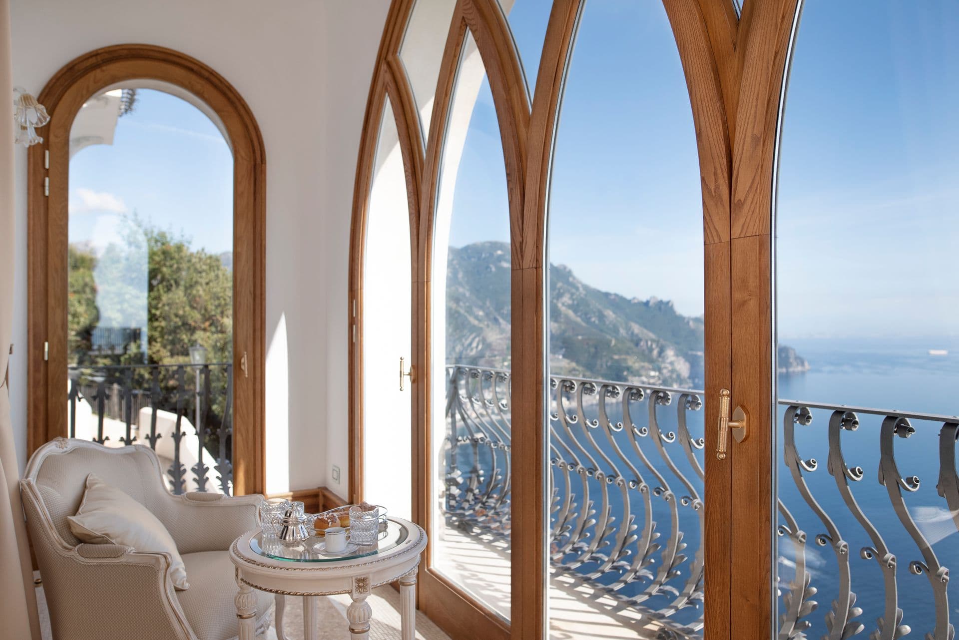 Wrought-iron balcony framed by arched doors with sea views
