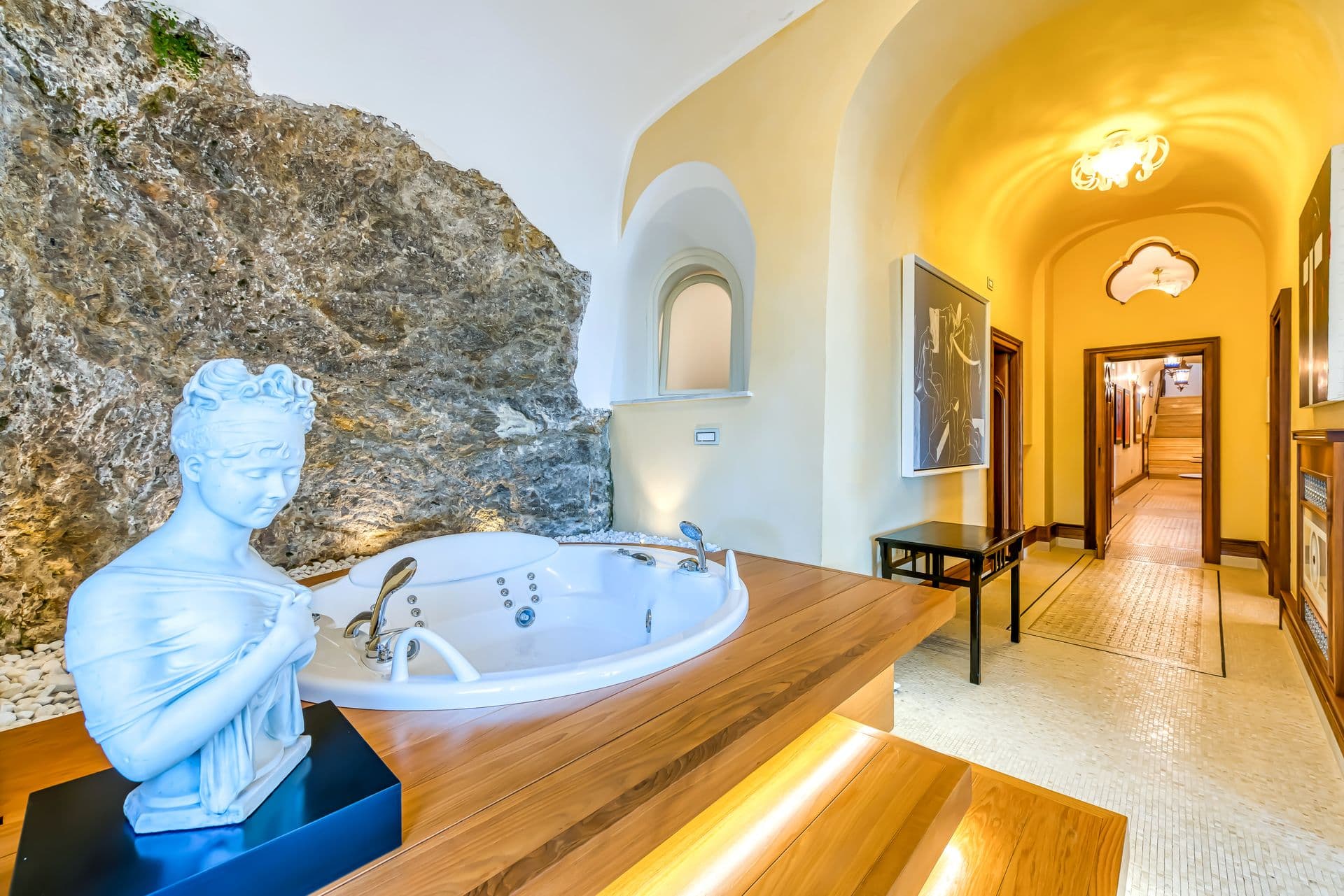 Sunken bathtub built into the natural rock face beside a classical bust