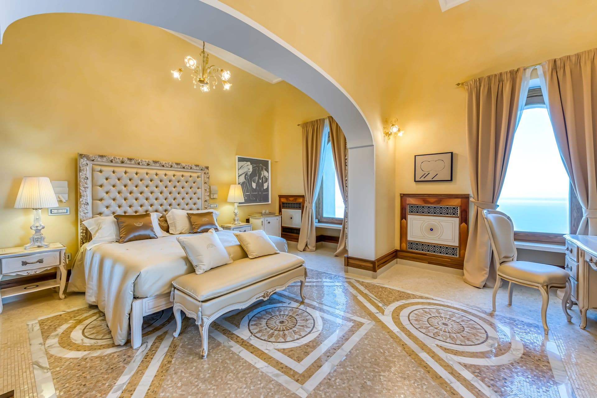 Vaulted guest bedroom with upholstered headboard and sea-view window