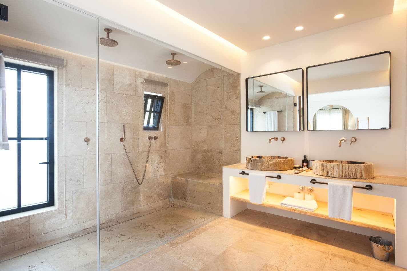 Stone bathroom with double vanity basins and walk-in shower