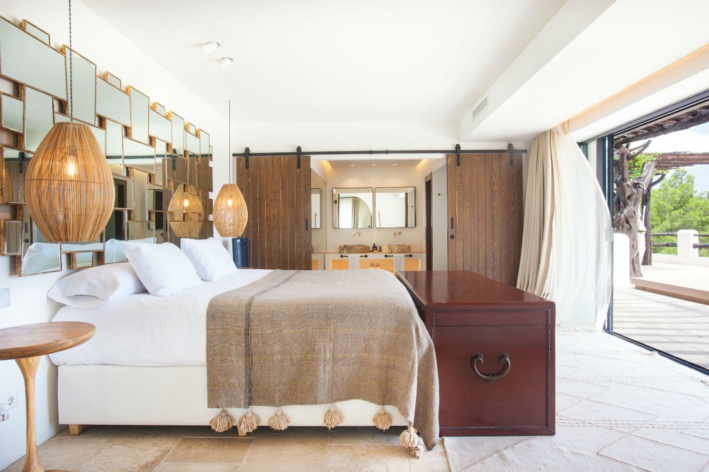 Bedroom with woven pendant lights and doors opening to a terrace