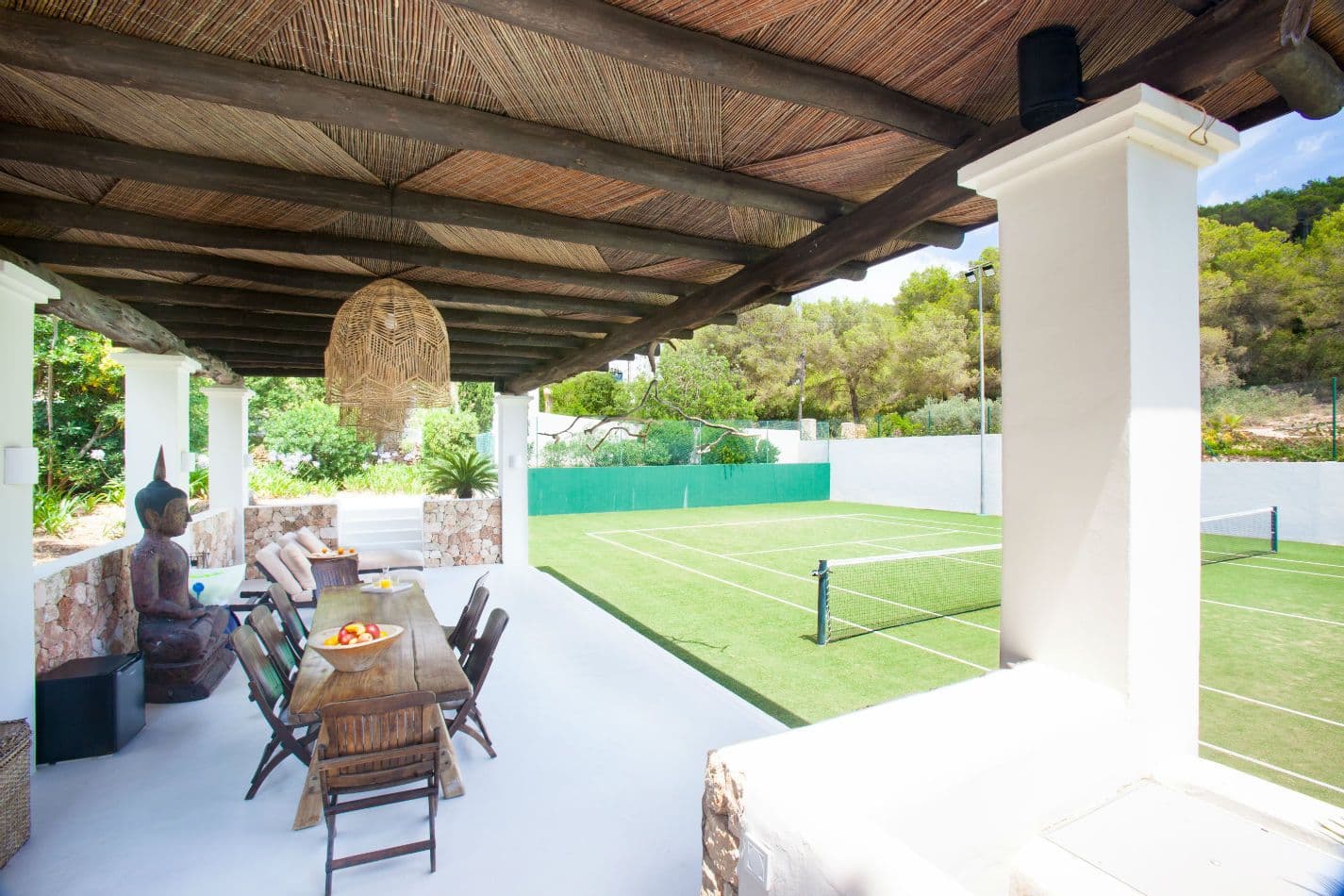 Covered terrace dining table beside a stone garden statue
