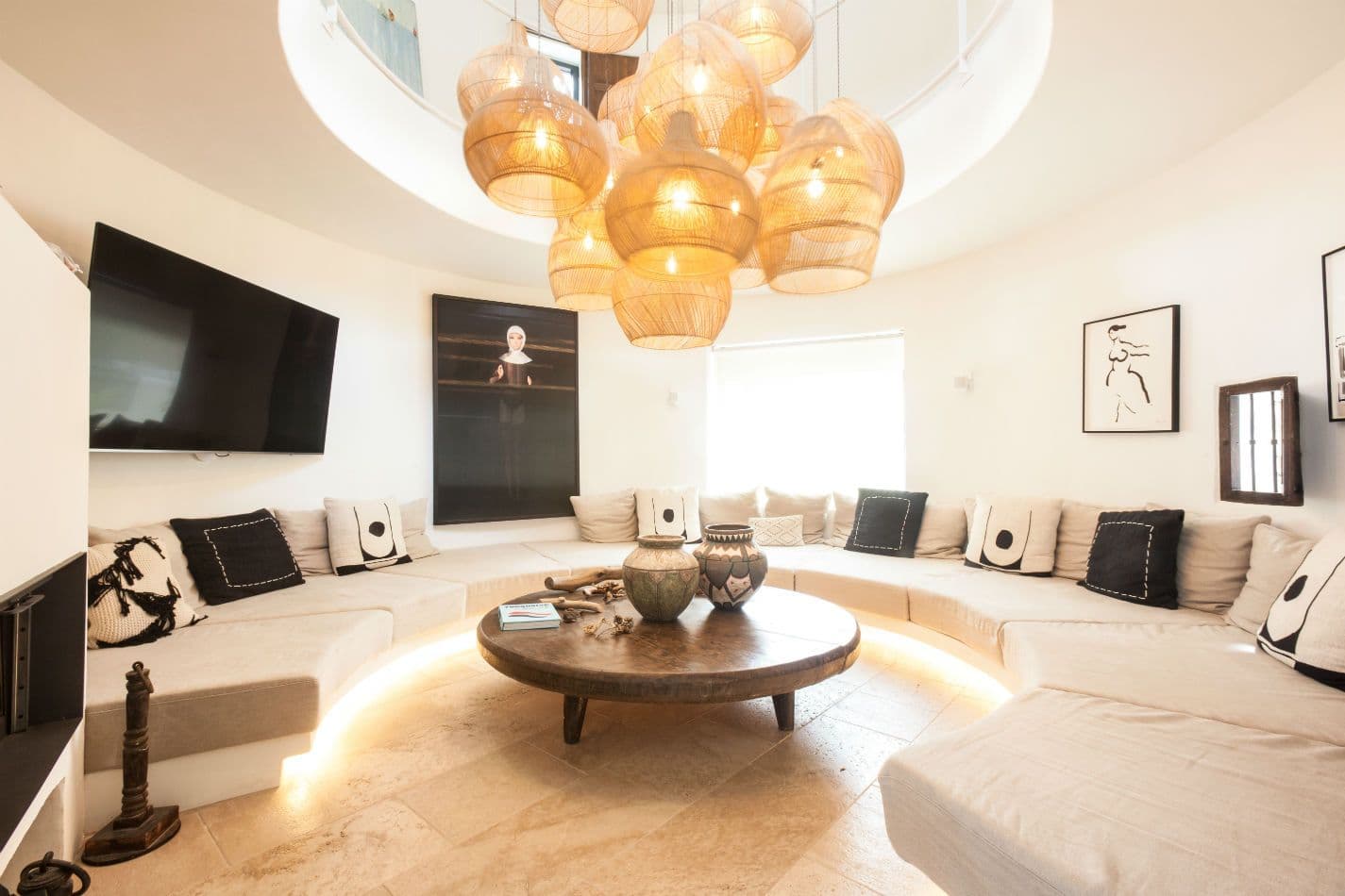 Circular living room with rattan pendant lights and wraparound sofa