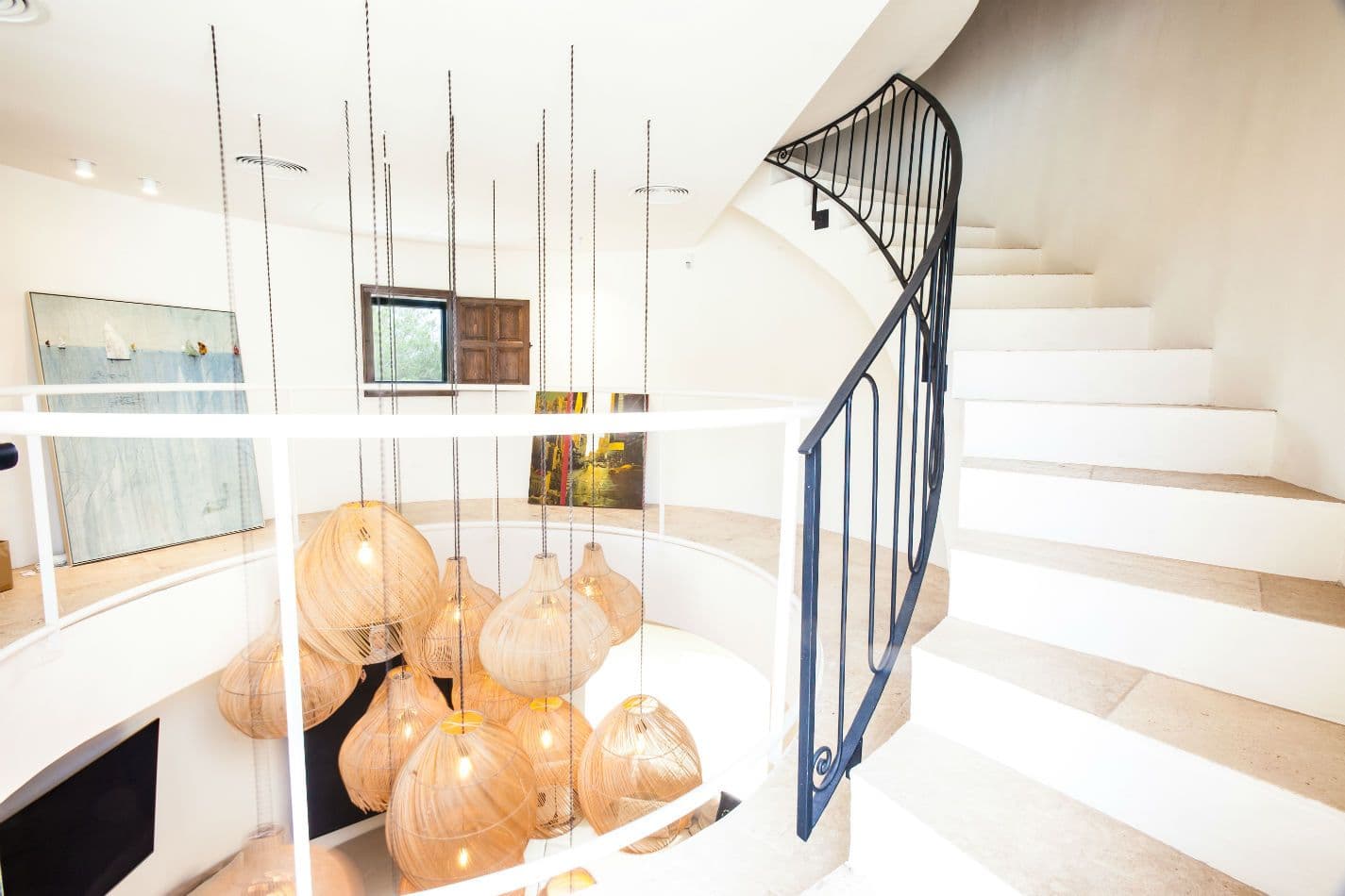 White spiral staircase beneath a skylight with hanging lanterns
