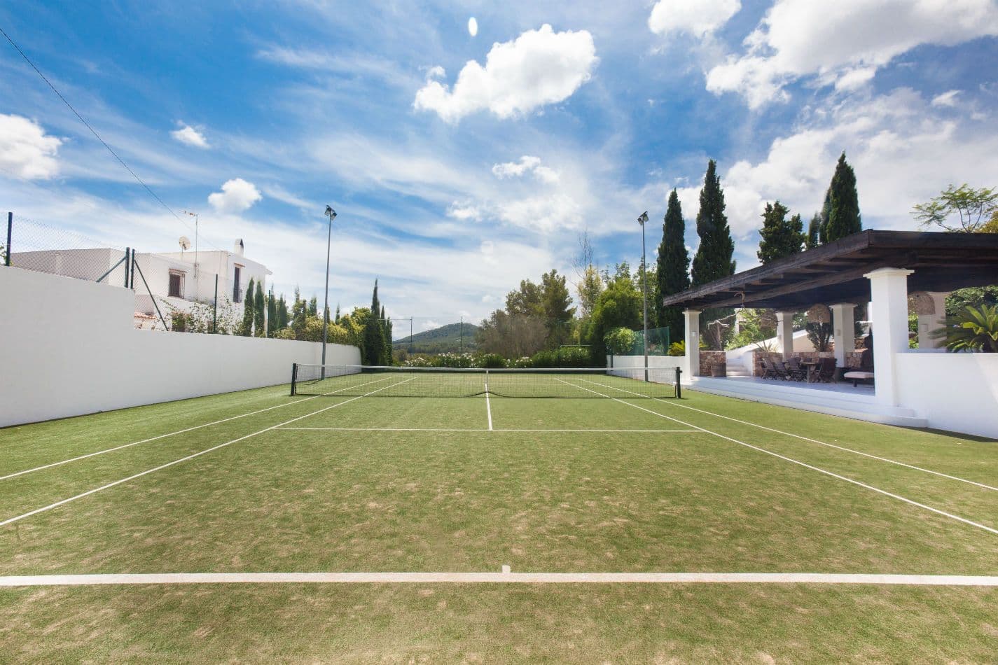 Private grass tennis court bordered by cypress trees