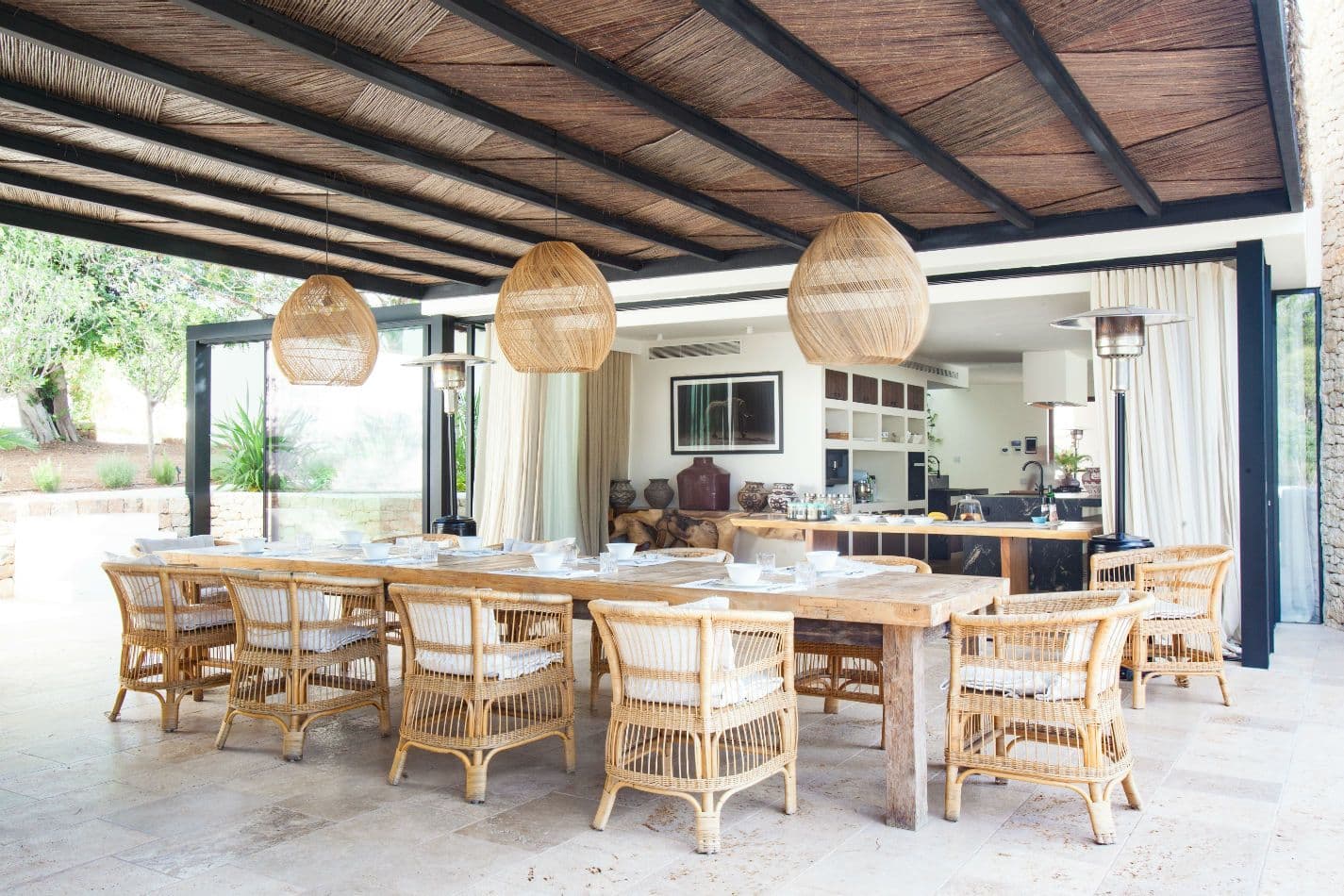 Long outdoor dining table set under a wood-beamed terrace