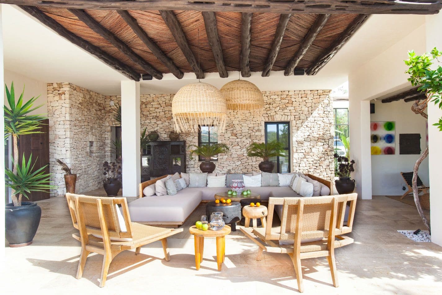 Covered terrace lounge with rattan pendant lights and beamed ceiling
