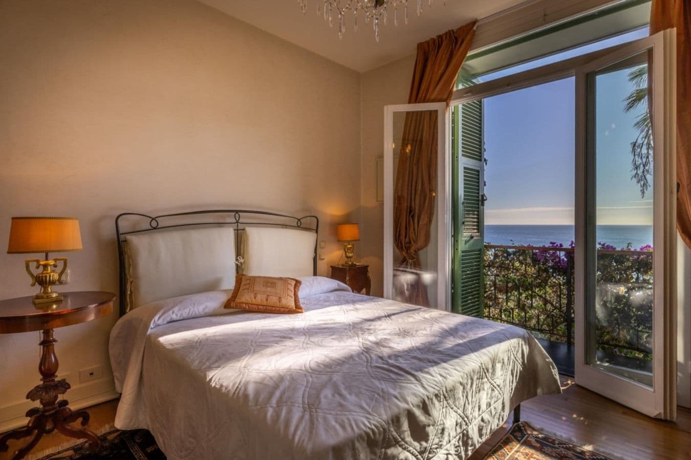 Bedroom with brass bed frame and sea-view balcony at On the Emerald Coast, Rapallo