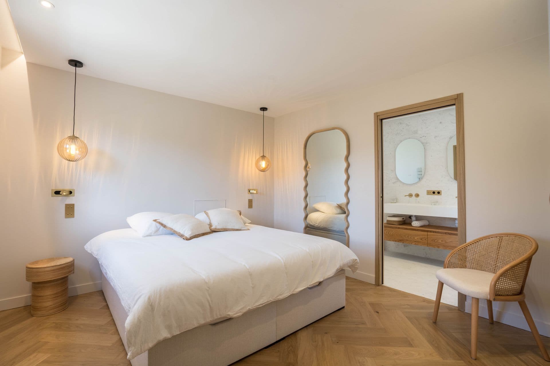 Bedroom with a scalloped arched mirror and rattan pendant lighting