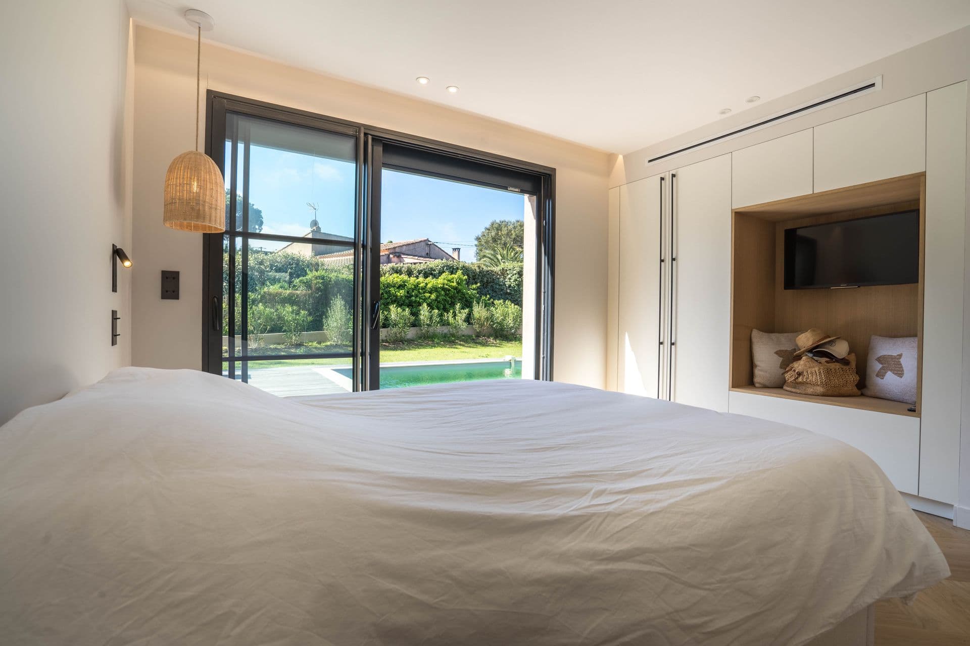 Bedroom with a full glass wall sliding open to the pool terrace