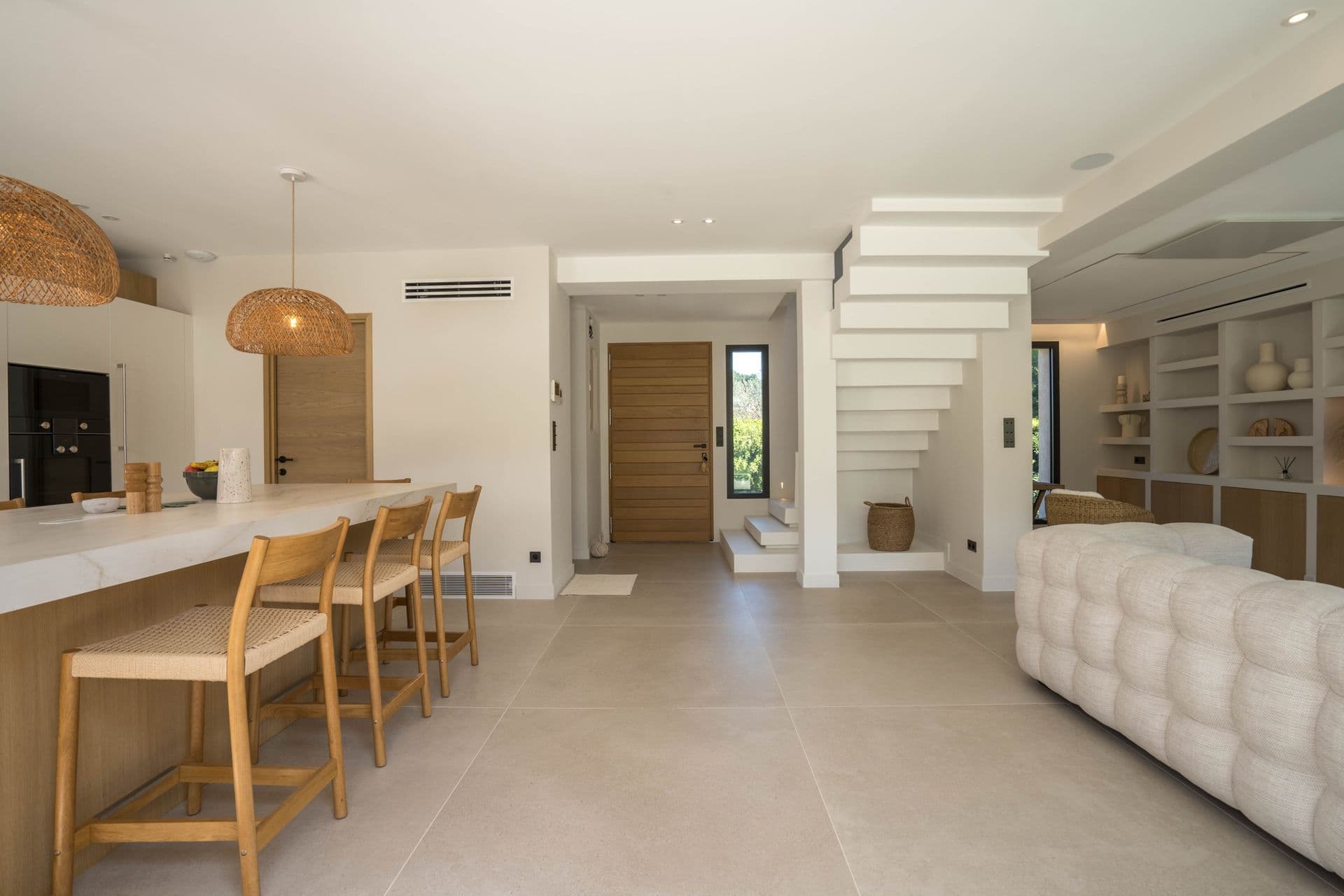 Kitchen with long wooden island and woven bar stools for eight