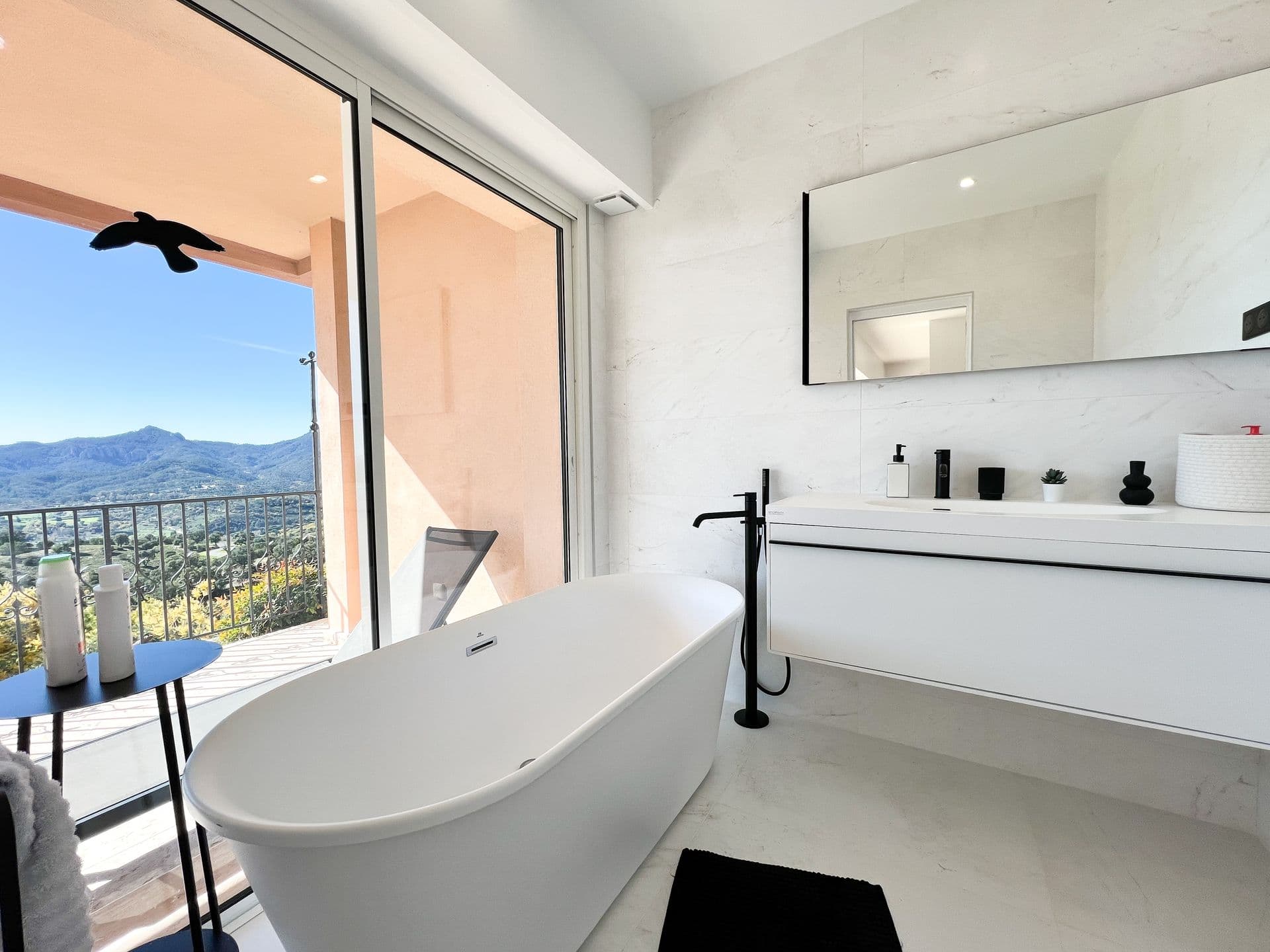 Bathroom with freestanding tub positioned beneath a window with hillside view at Golden Escape