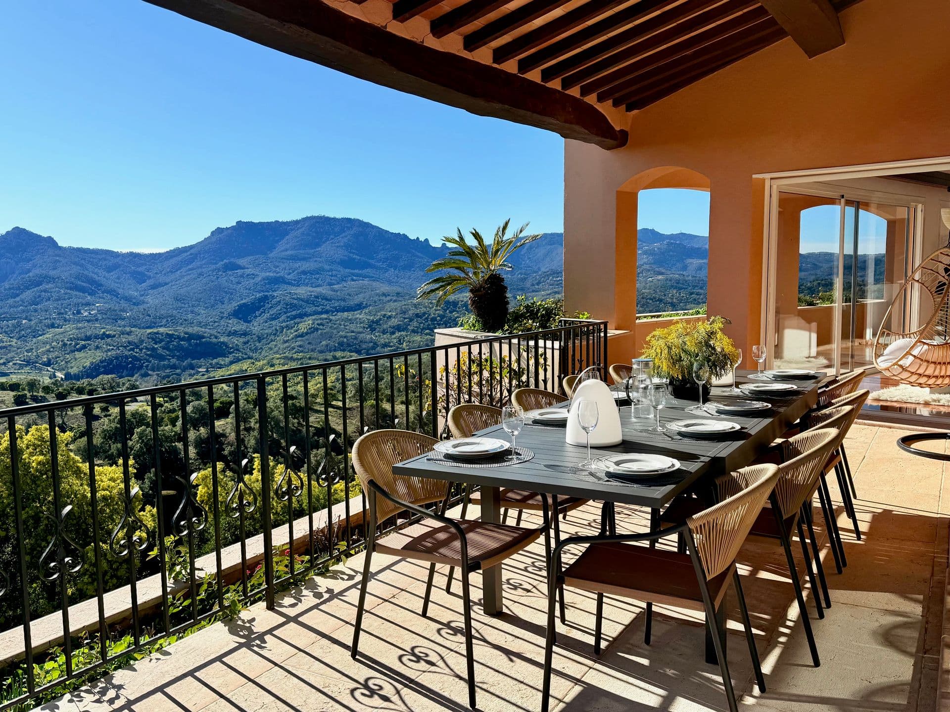 Covered terrace dining table for eight beneath timber beams with mountain views at Golden Escape