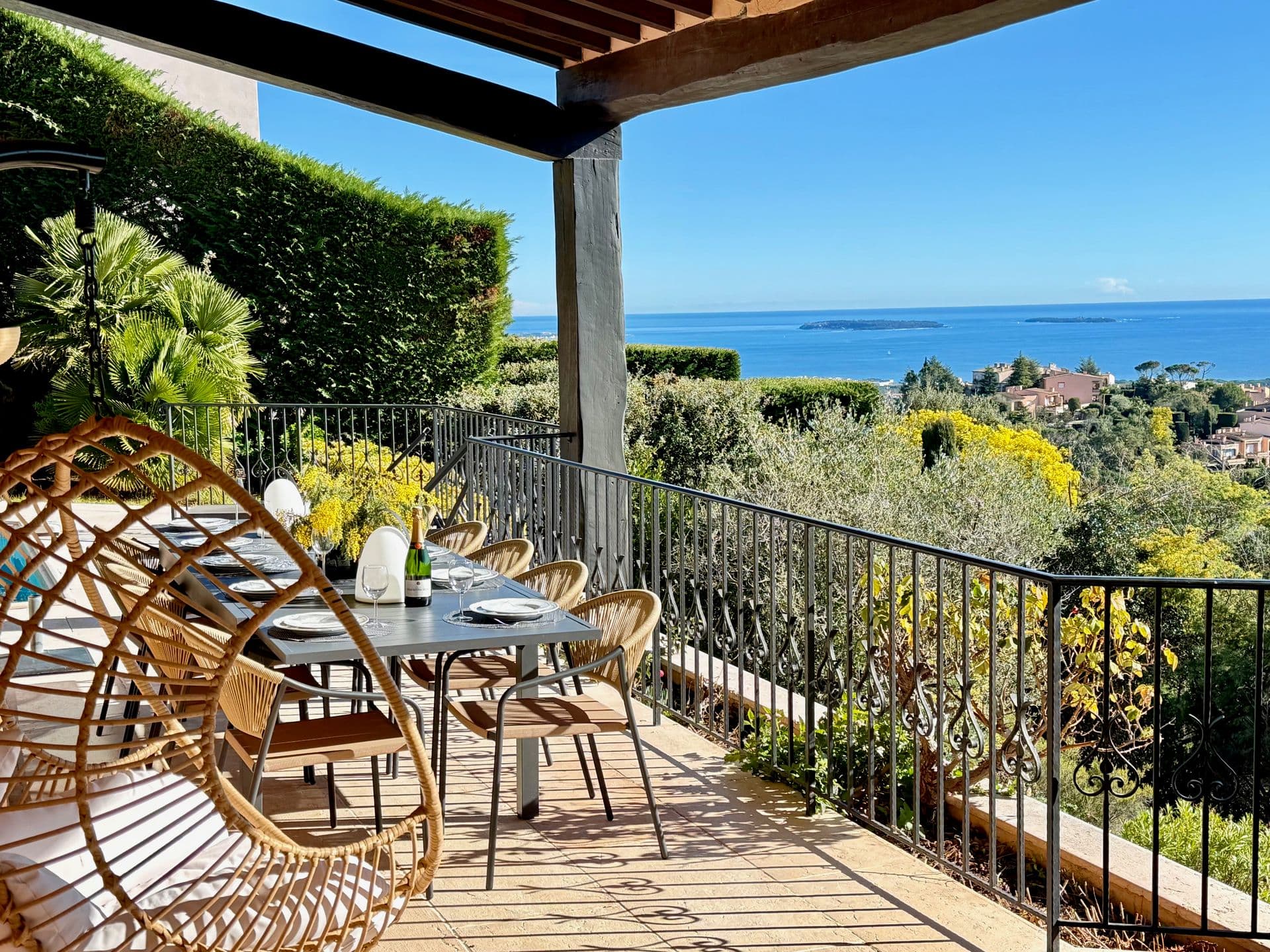 Rattan lounge chairs and hedged terrace with distant sea view at Golden Escape