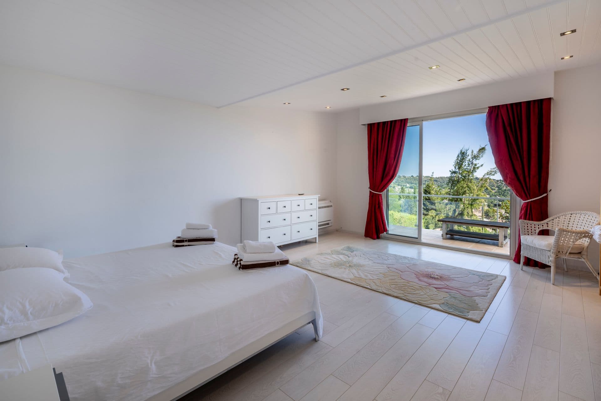 Guest bedroom with red curtains and garden view at Olive and Sea