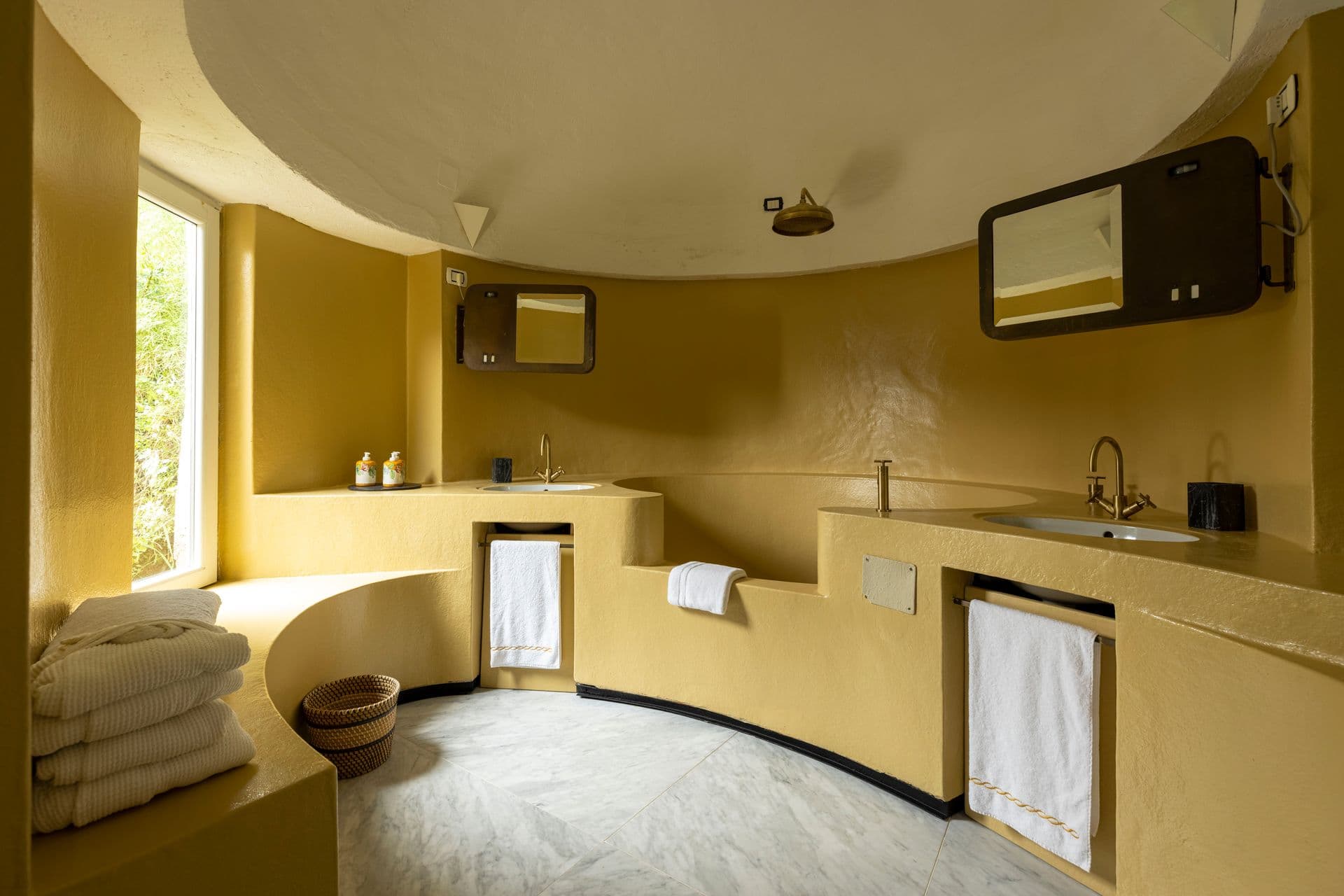 Curved ochre-toned spa bathroom with sculptural sink and towels