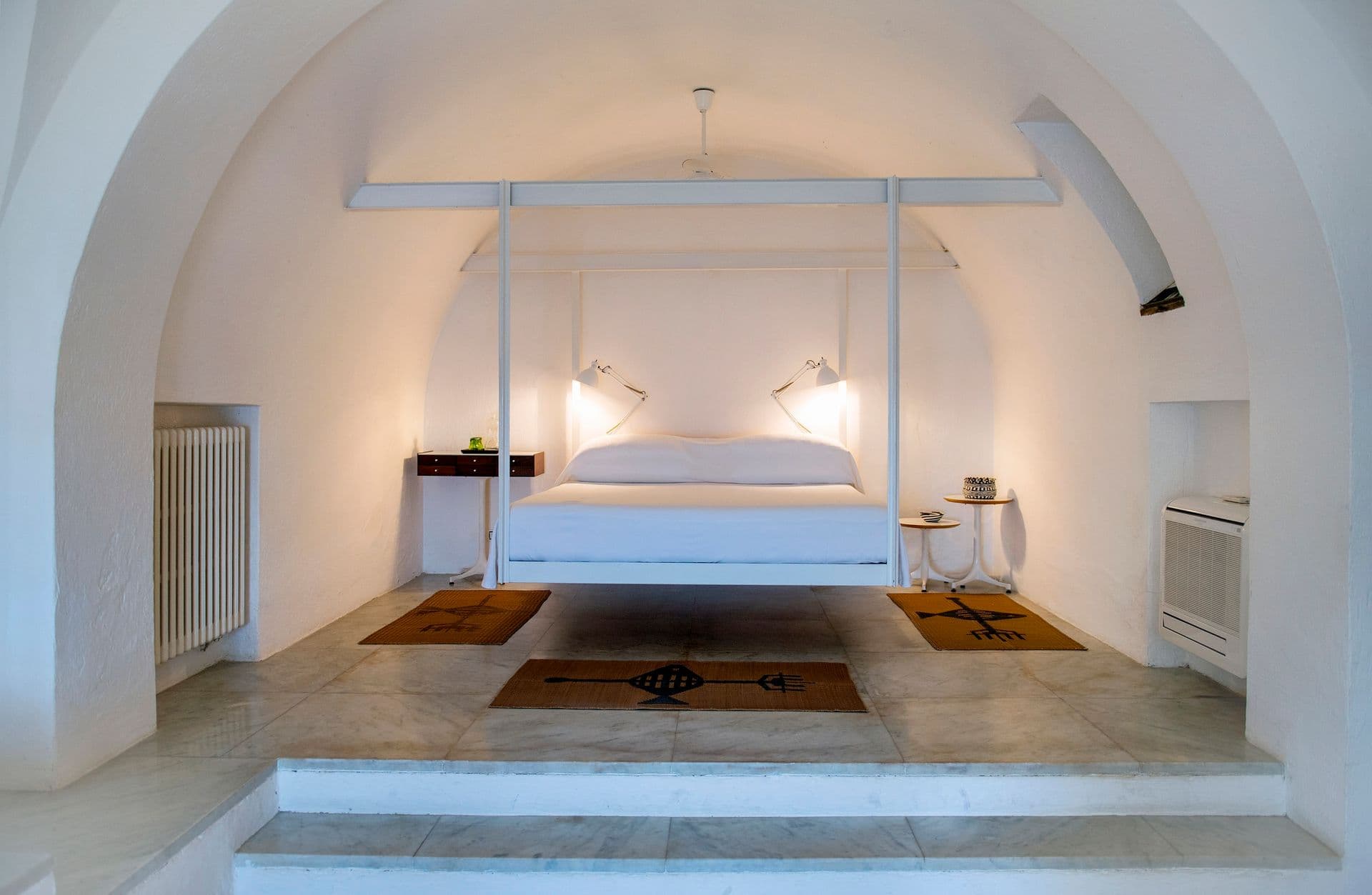 Bedroom with a raised platform bed beneath a sculptural stone arch