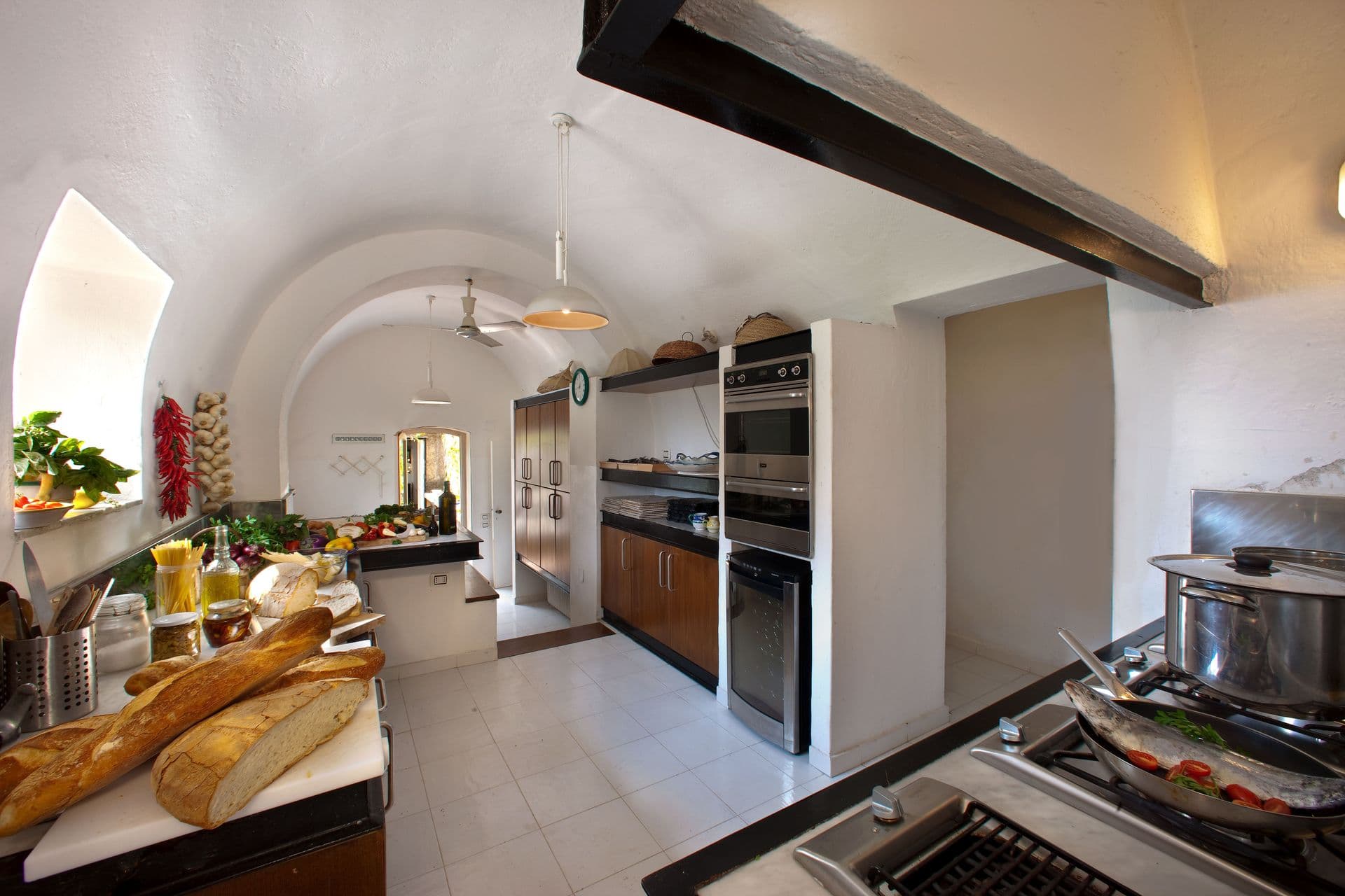 Vaulted stone kitchen with fresh produce laid out on the counter