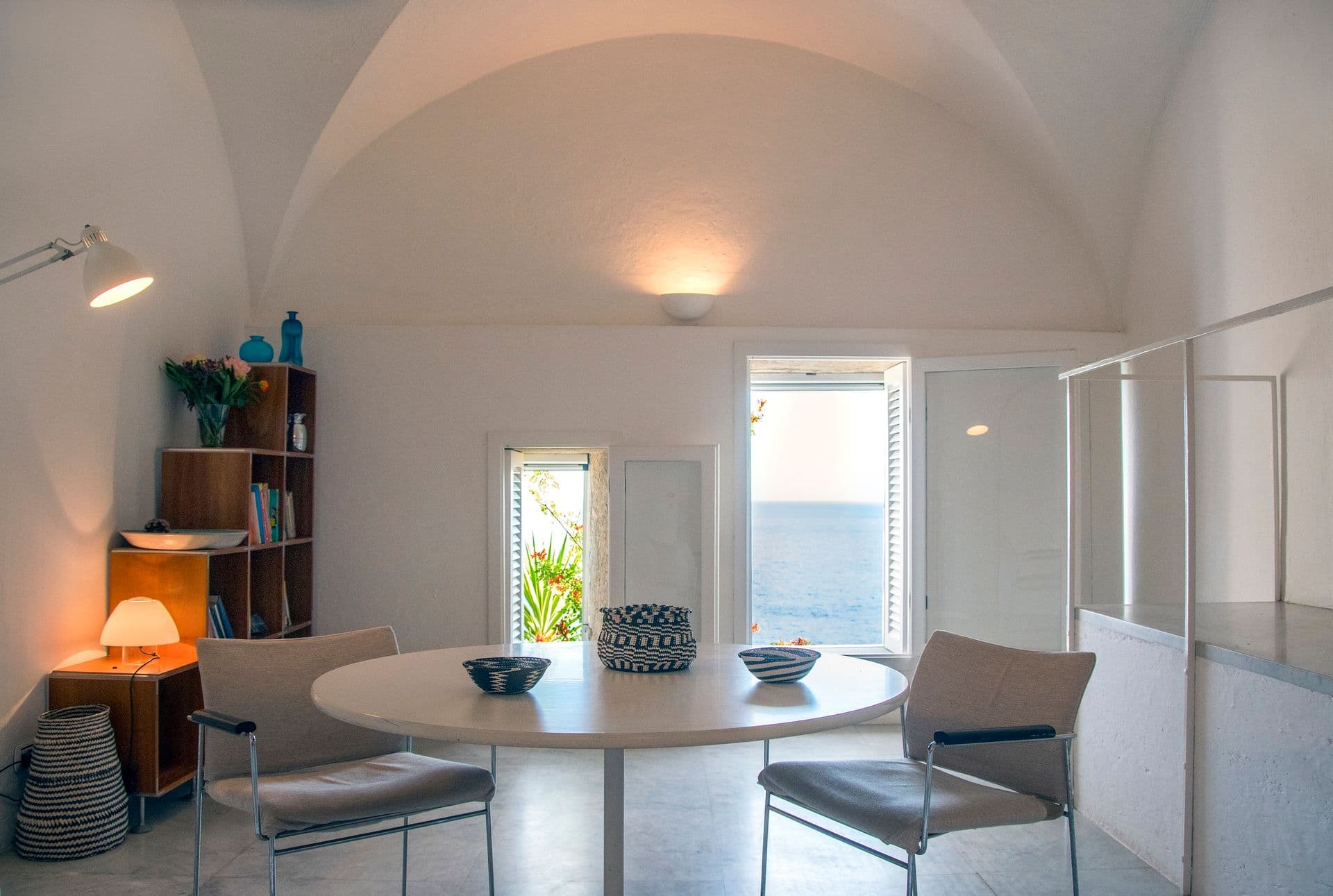 Reading nook with round table and chairs beneath a vaulted white ceiling