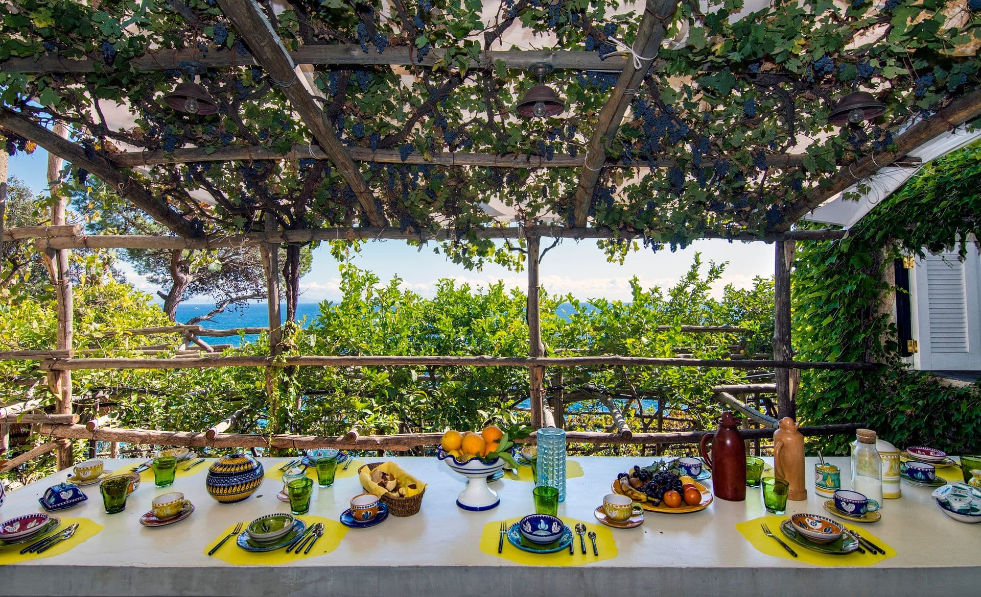 Lemon-vine pergola shading an outdoor dining table laid with colourful plates